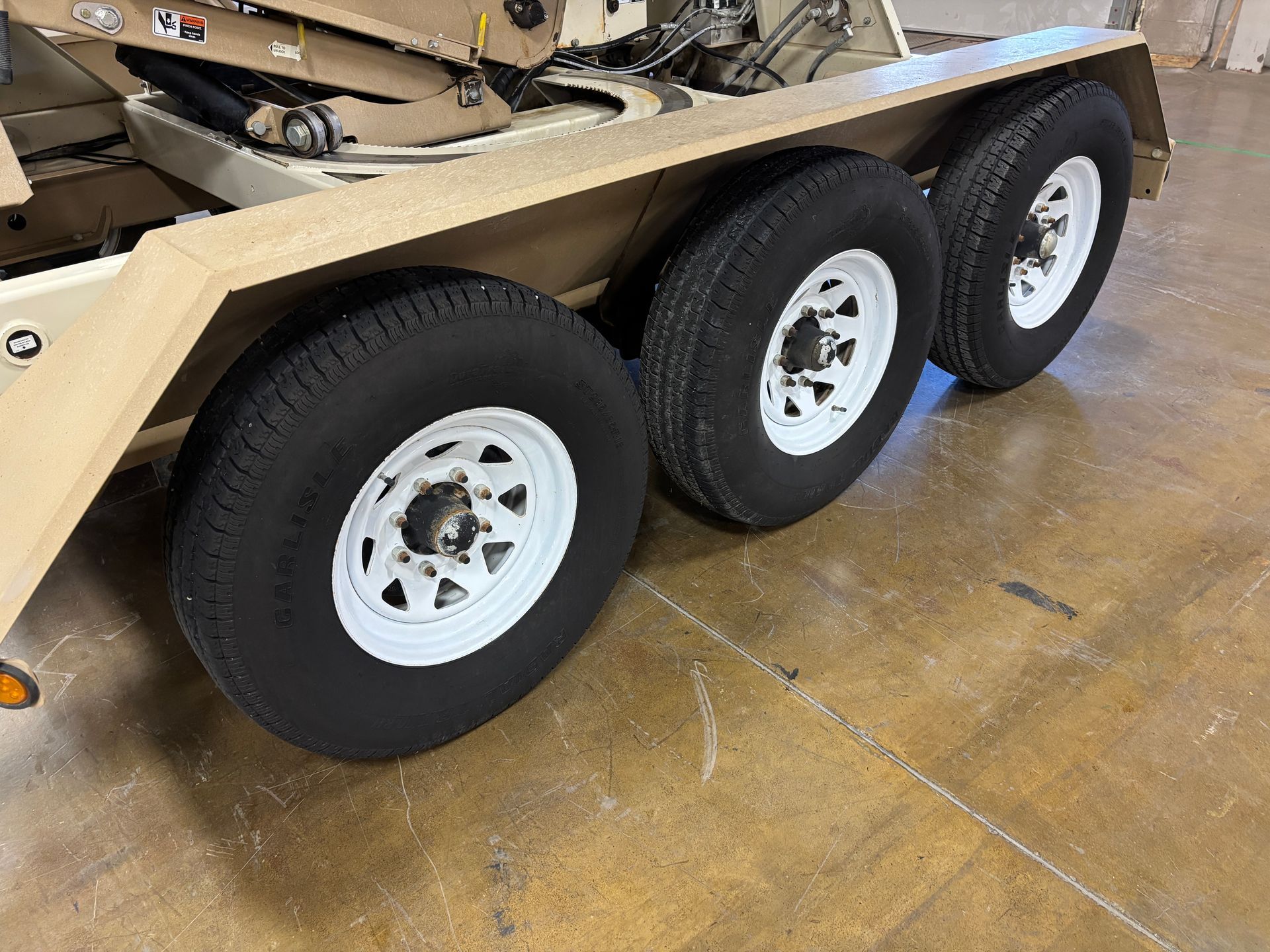 Tan trailer with three tires, white rims.