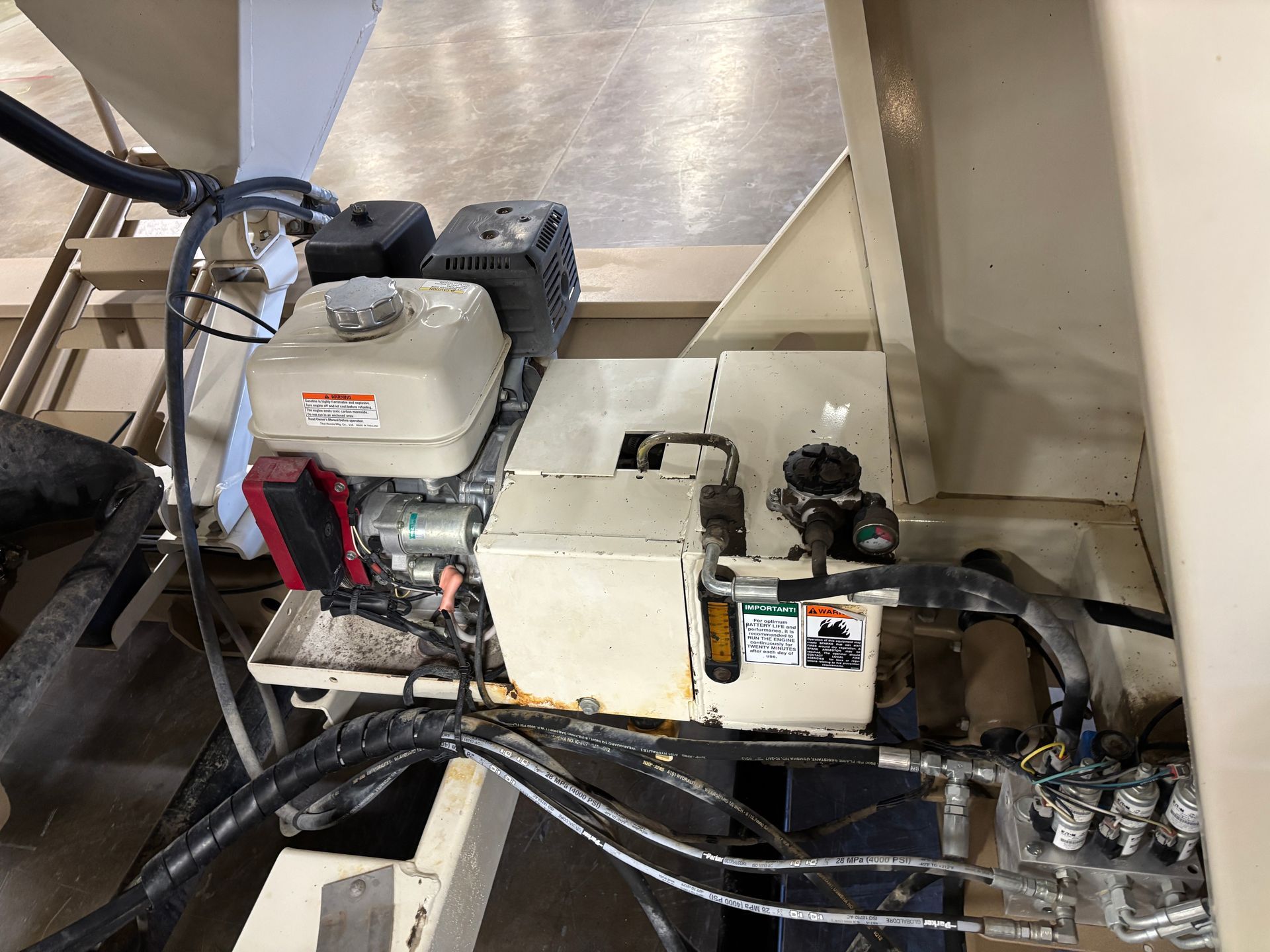 An engine inside of a piece of industrial equipment, featuring a gas tank and hydraulic components.