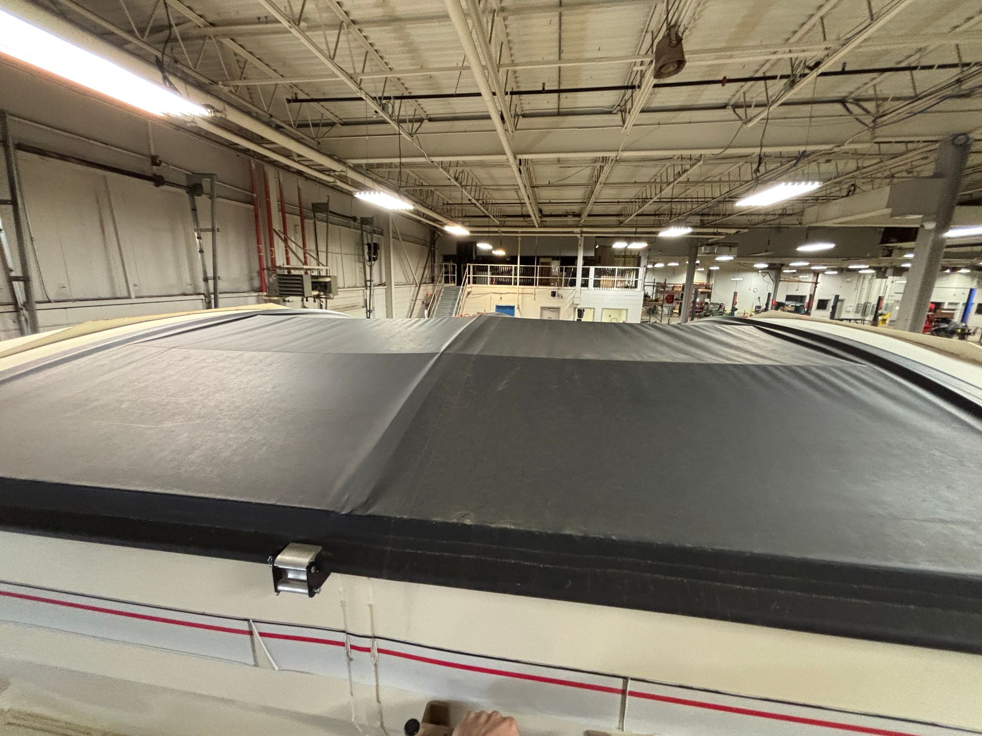 Black fabric stretched across a curved frame in a large industrial setting.