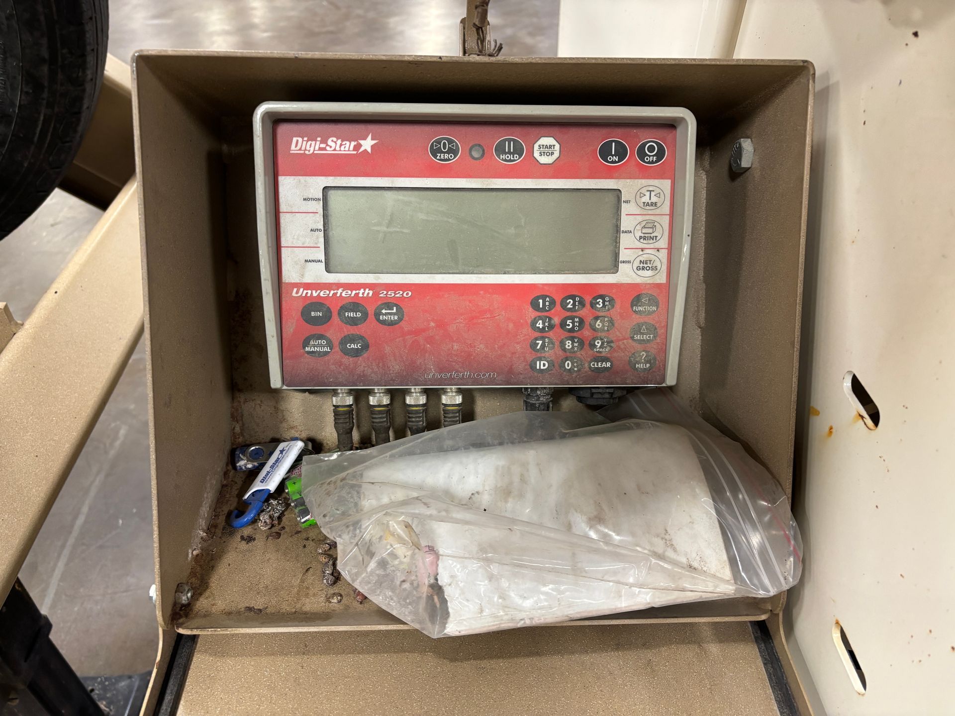 Red and white digital scale display inside a beige enclosure, containing debris.