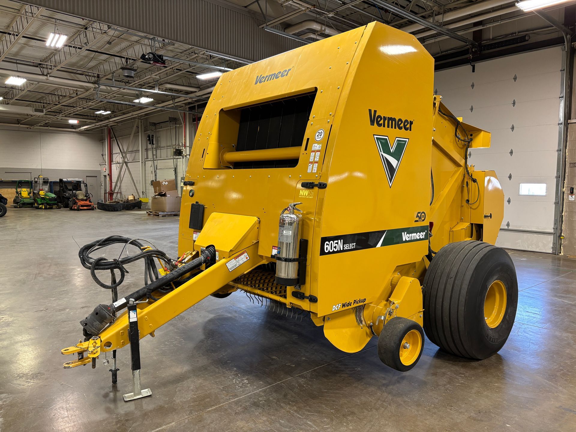 Yellow Vermeer round baler in an indoor setting, angled shot.