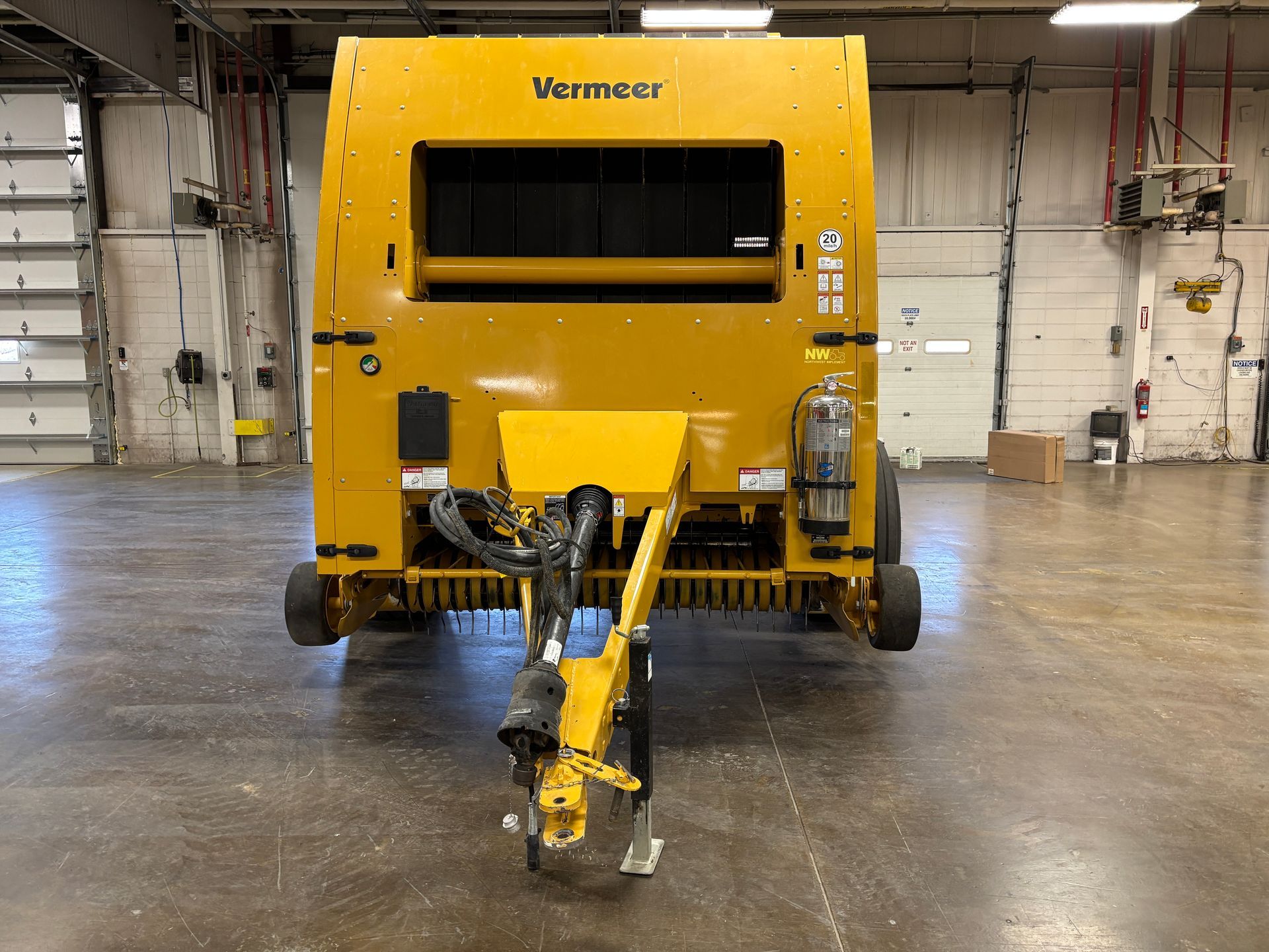 Yellow Vermeer round baler in an indoor setting, front shot.
