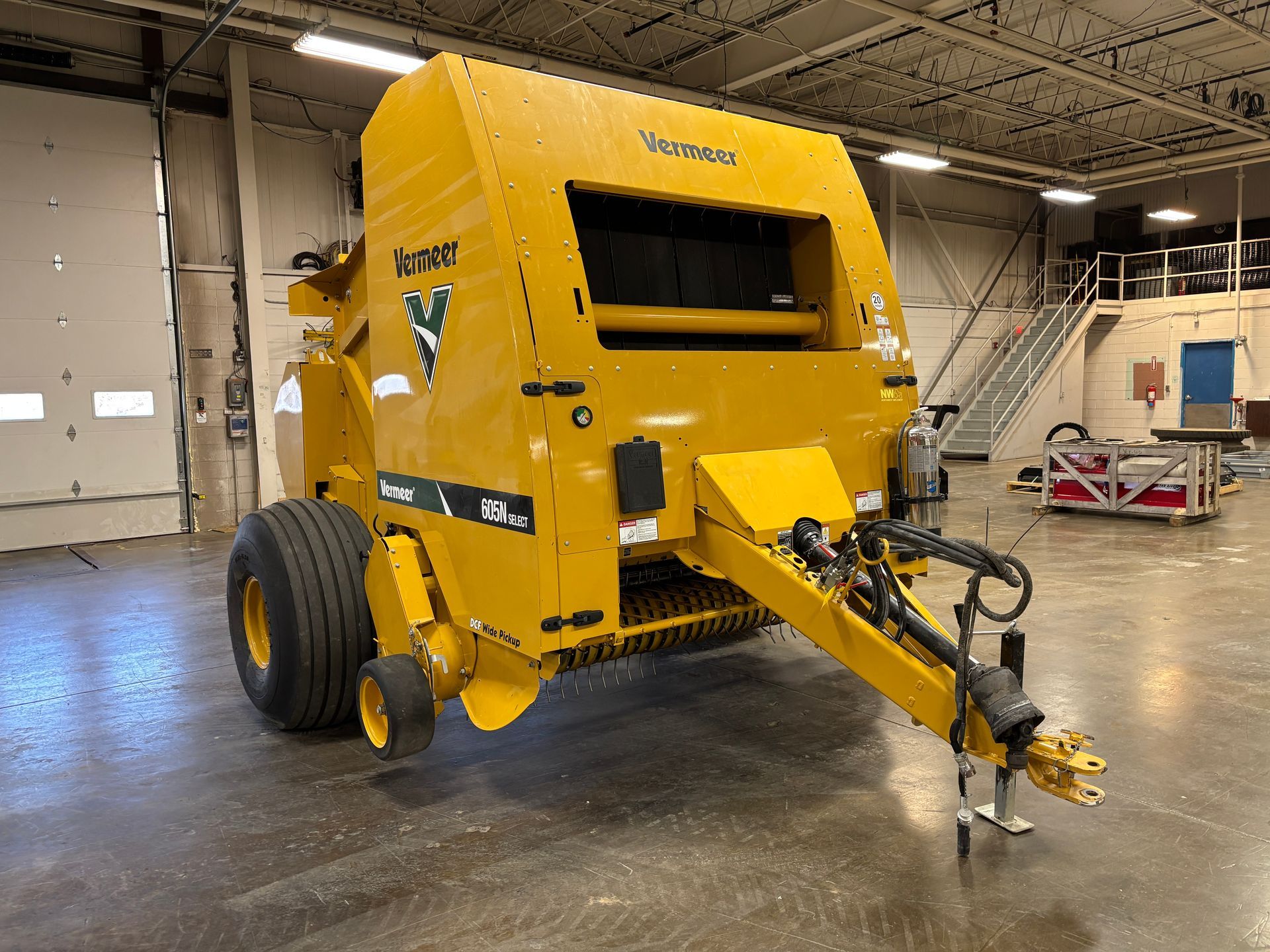 Yellow Vermeer round baler in an indoor setting, front angled shot.