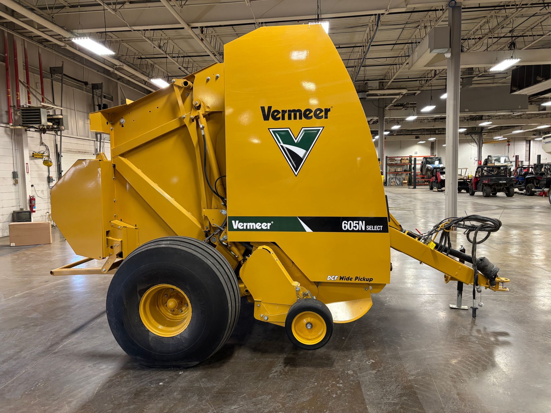 Yellow Vermeer round baler in an indoor setting, side view shot.