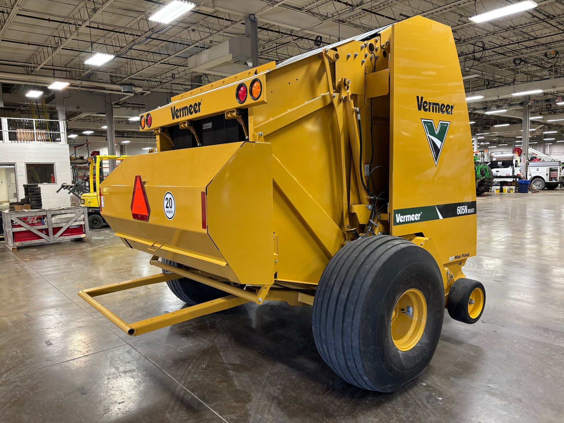 Yellow Vermeer round baler in an indoor setting, back angled shot.