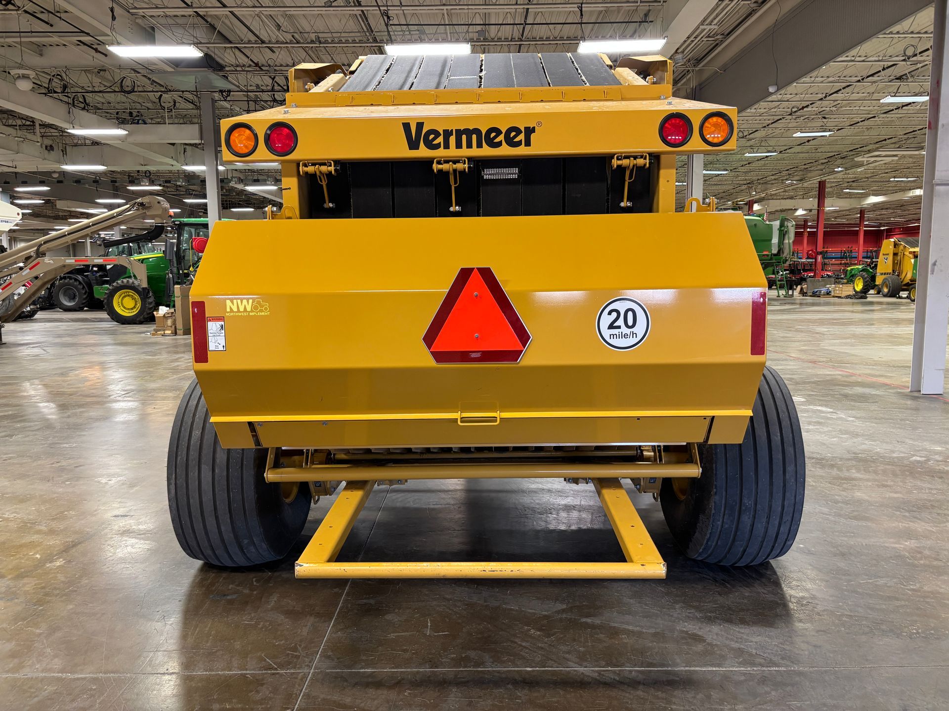 Yellow Vermeer round baler in an indoor setting, back shot.