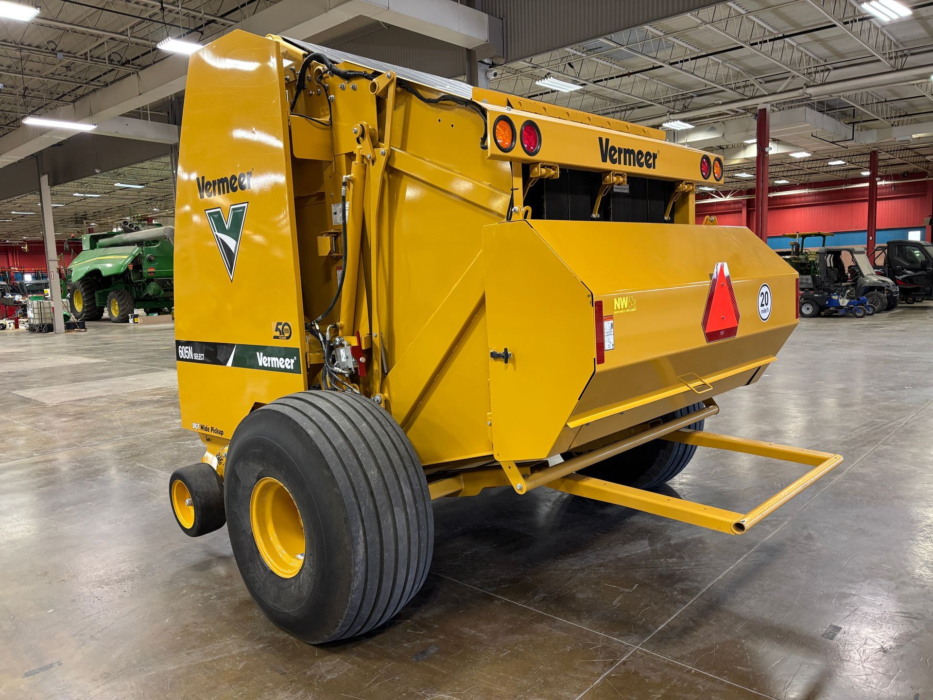 Yellow Vermeer round baler in an indoor setting, back angled shot.