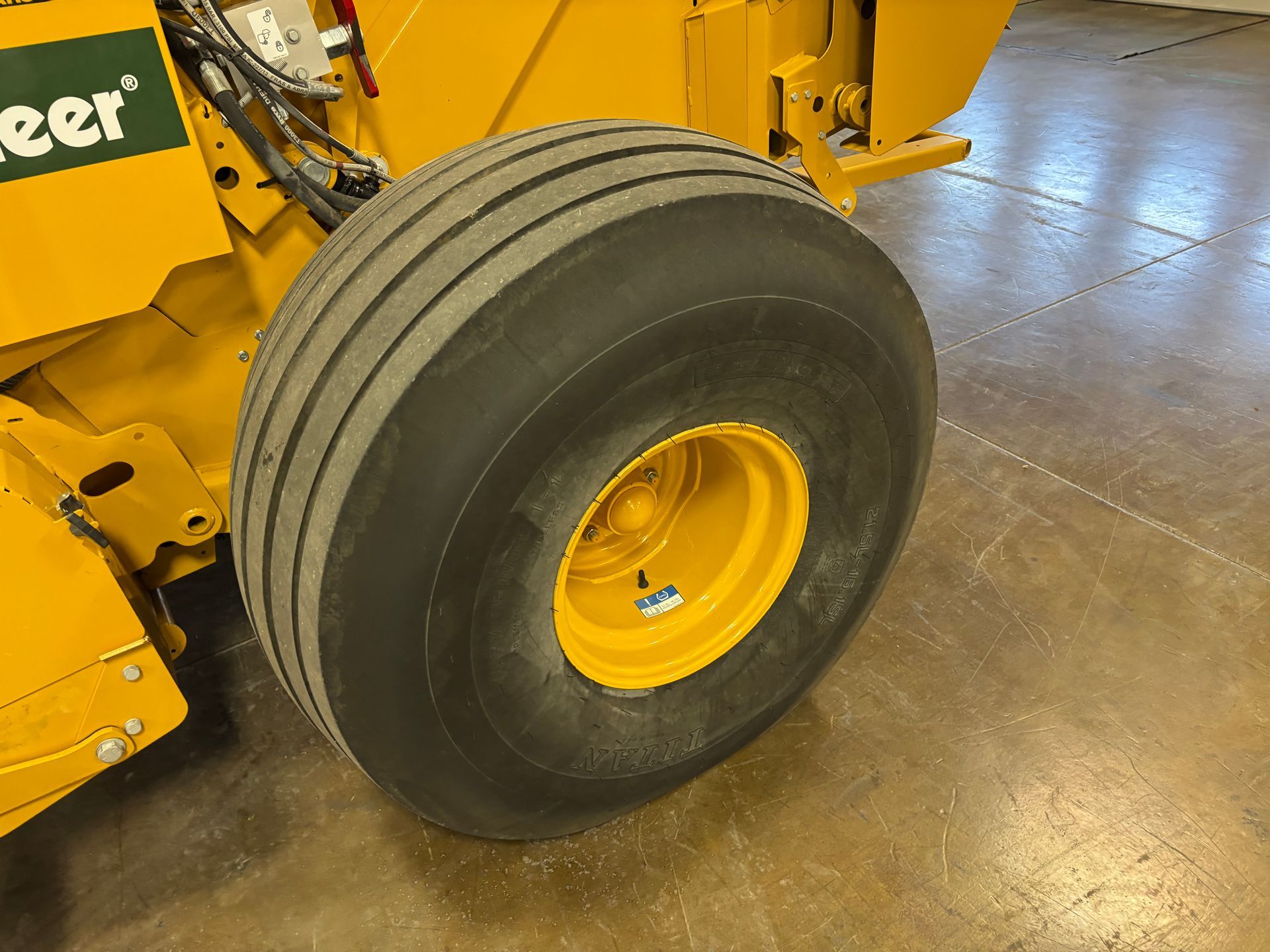 Yellow baler tire with a yellow wheel, on a concrete floor.