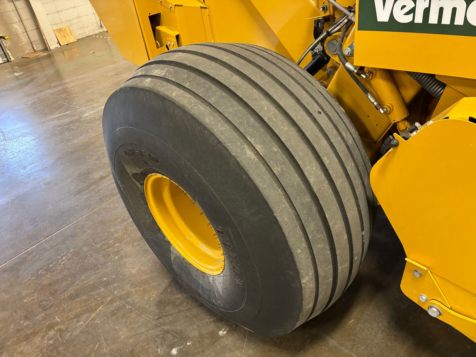 Yellow baler tire with a yellow wheel, on a concrete floor.