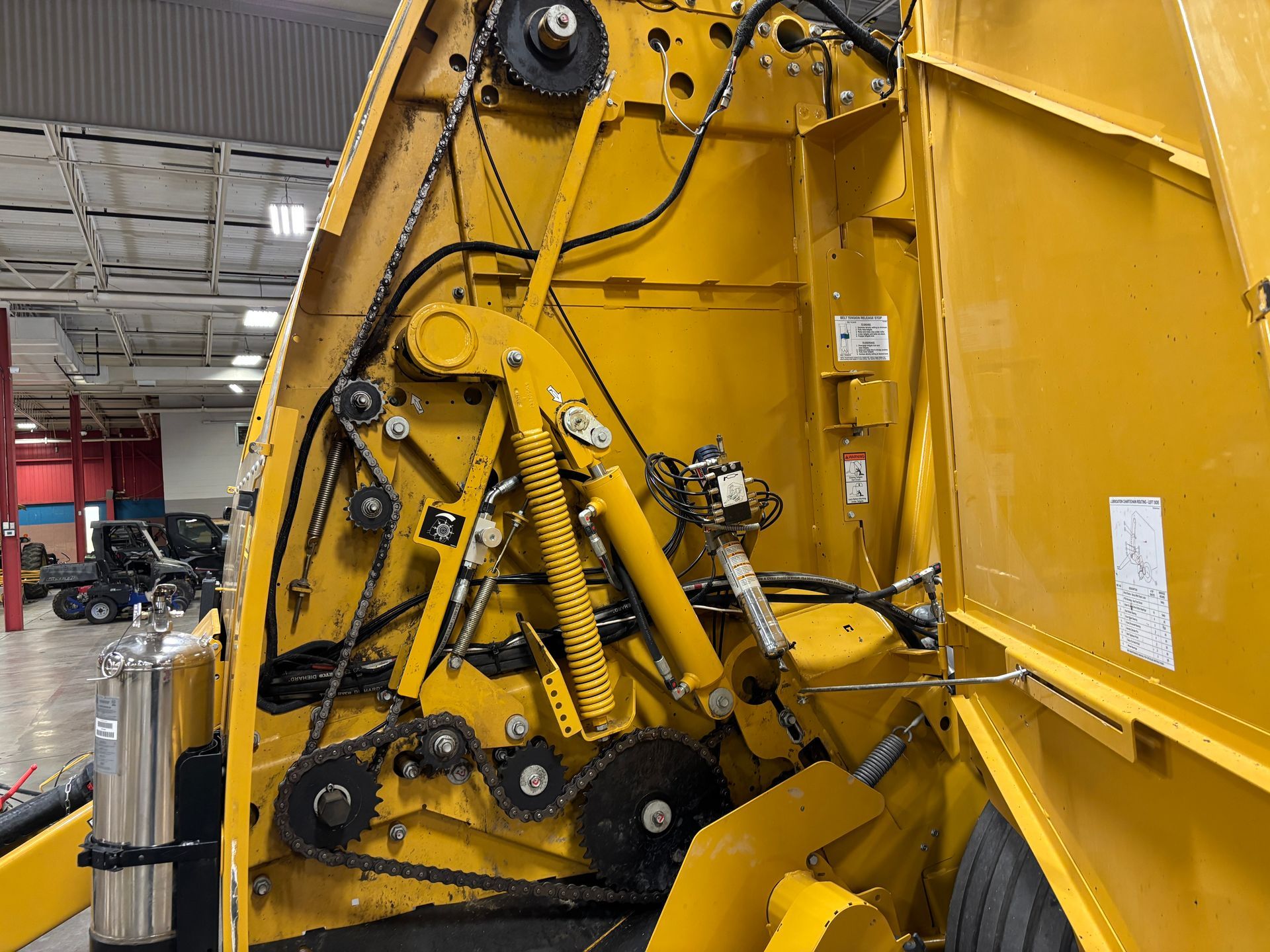 Yellow baler interior with belts, chains, and hydraulics.