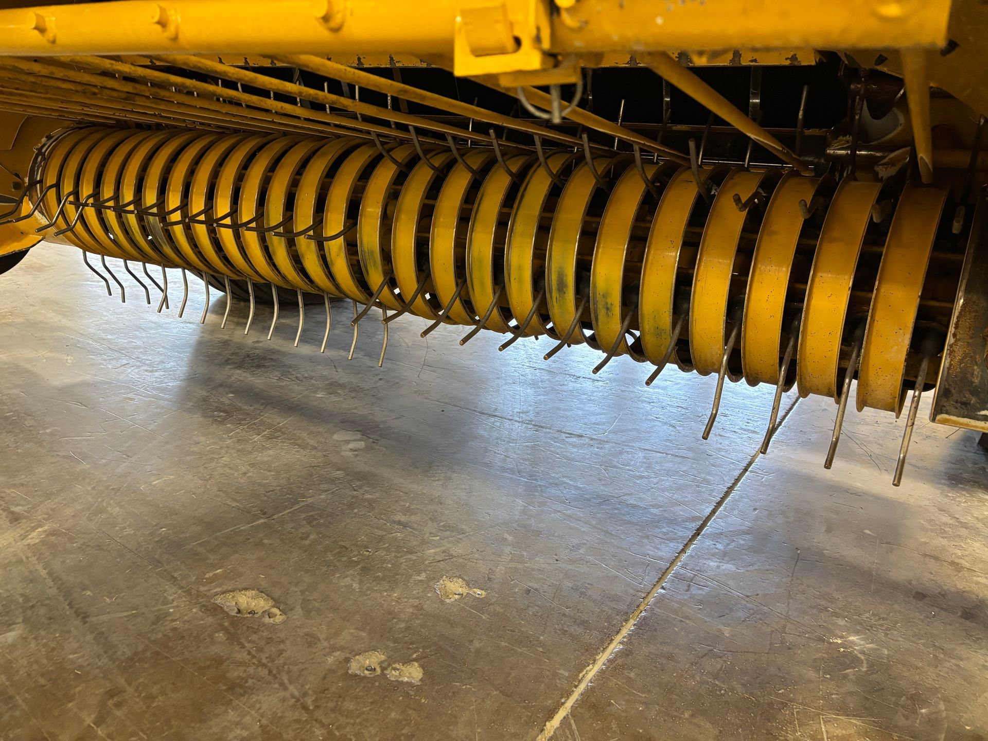Yellow hay rake with tines, close-up view.