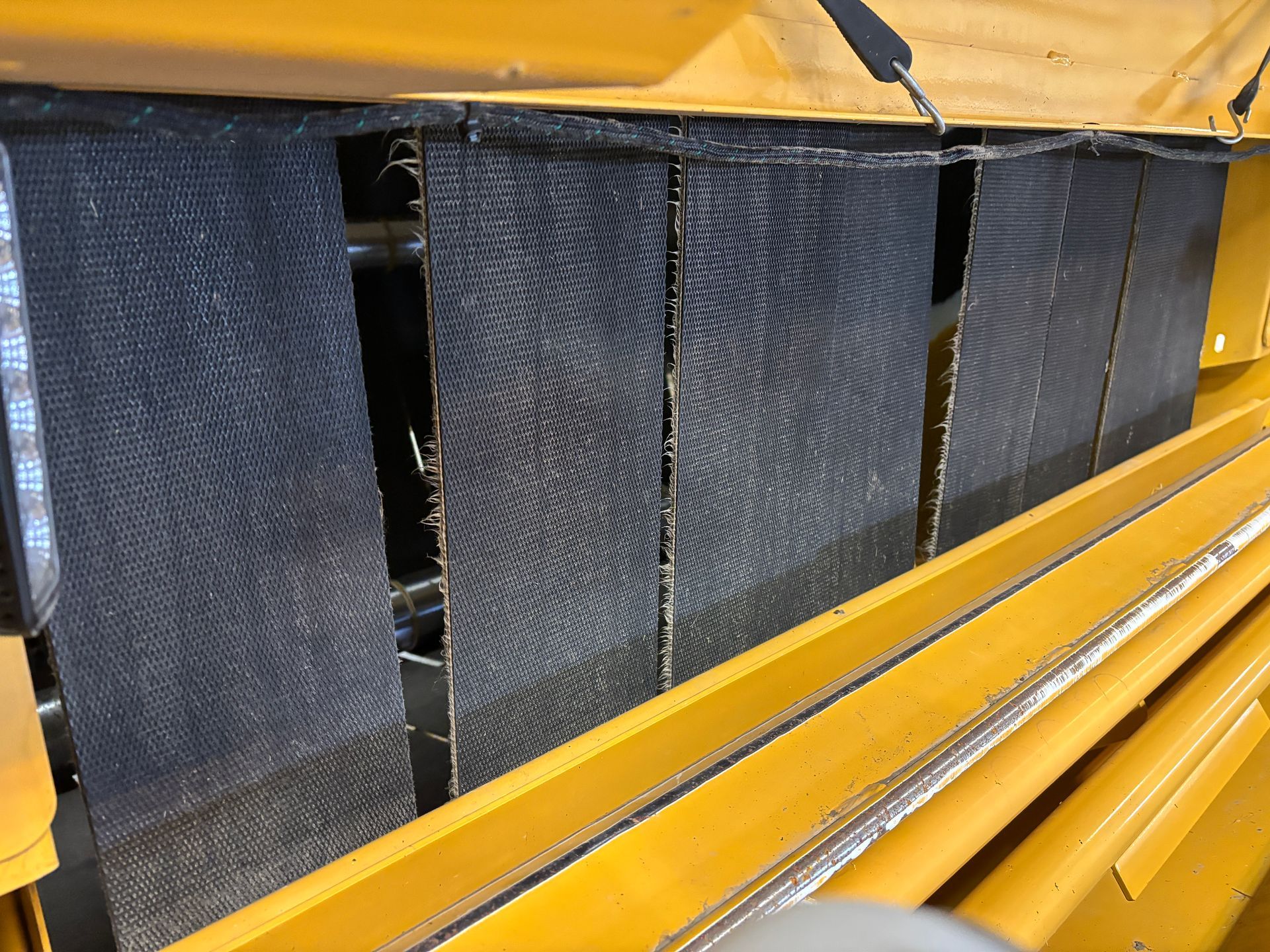 Black mesh screens inside a yellow machine compartment.