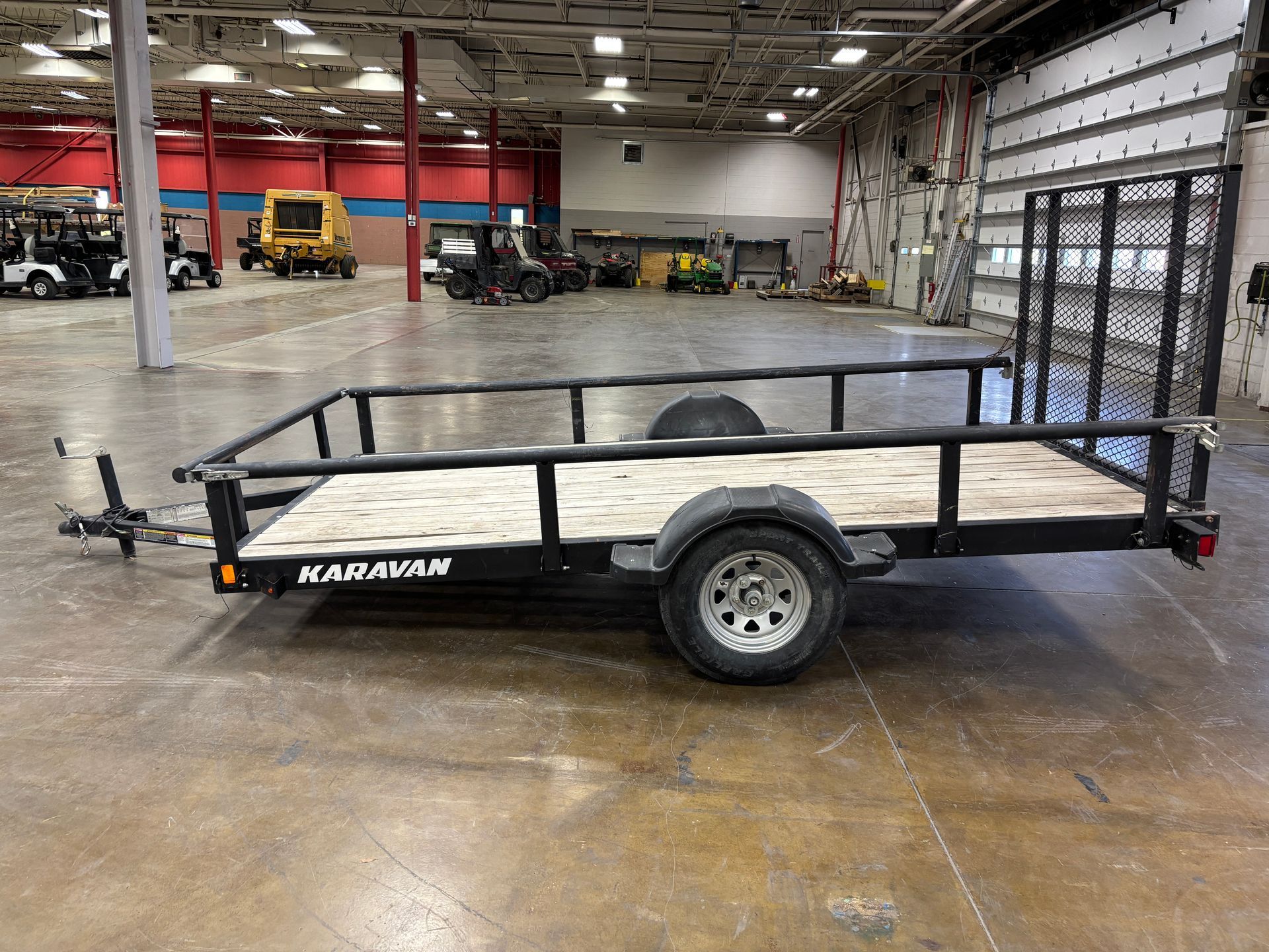 Black Karavan utility trailer with wooden bed, in a large warehouse.