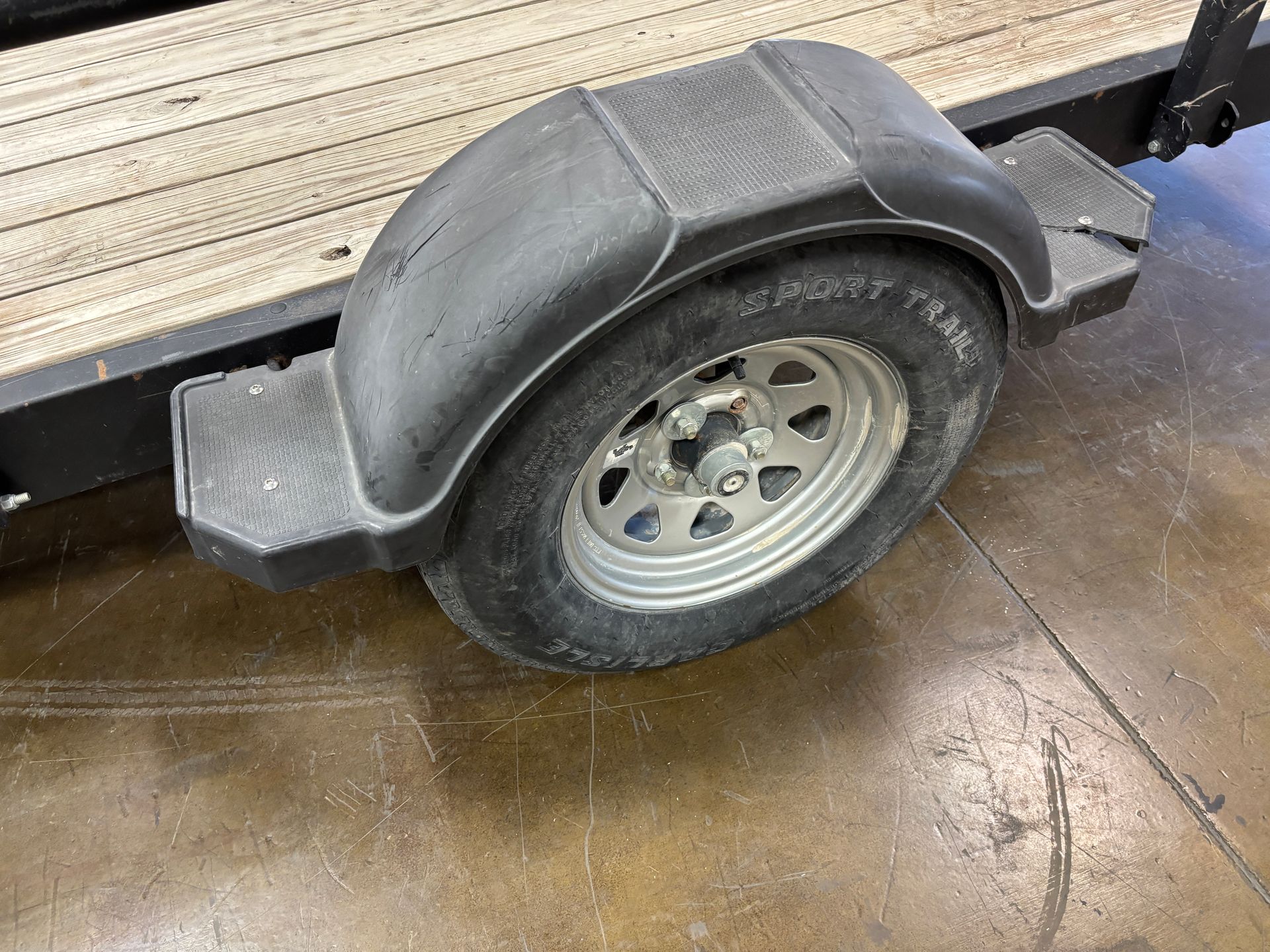 Black trailer tire with a black fender. Trailer deck is visible.