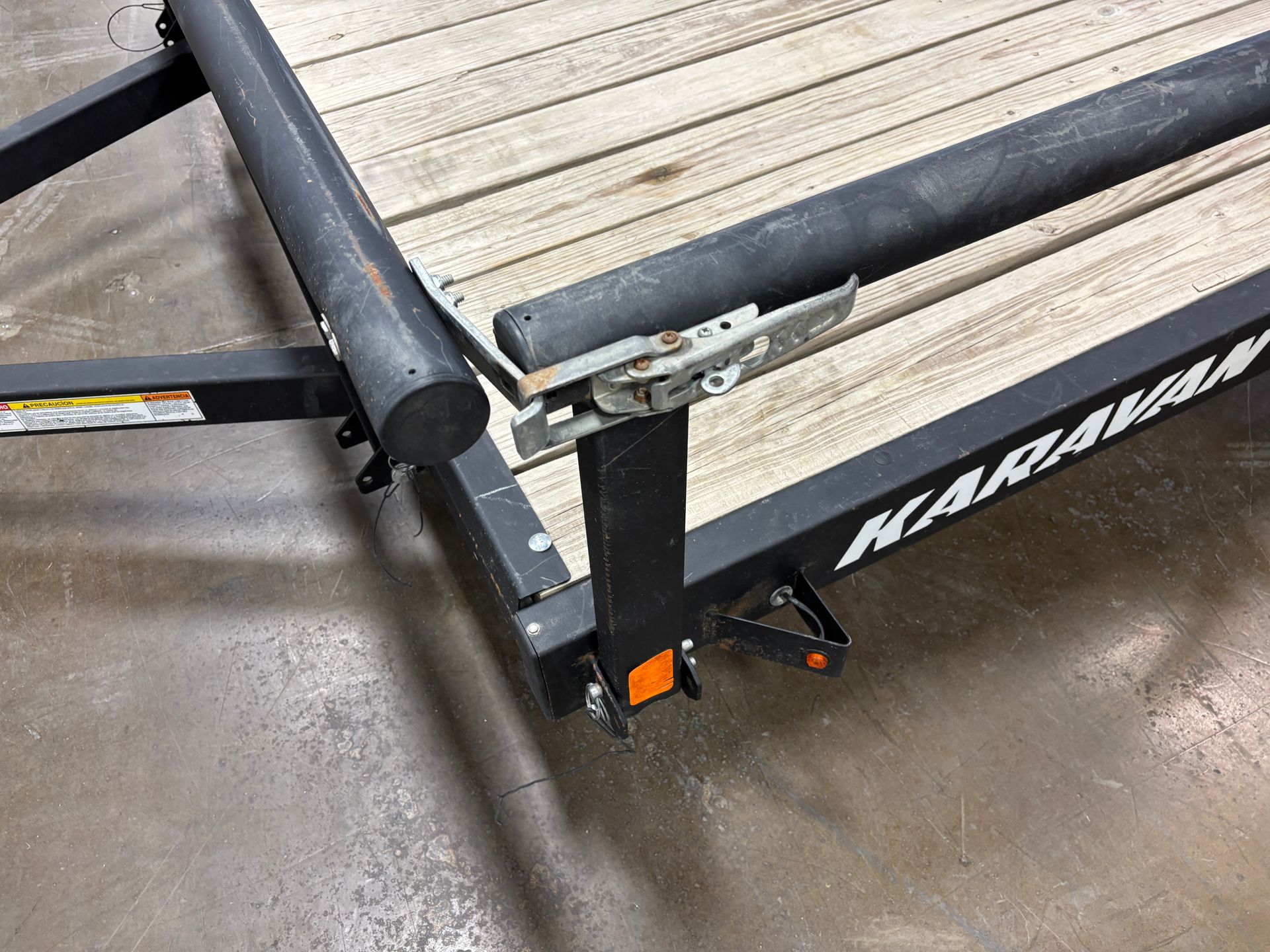 Black trailer with wooden planks and a support jack. 