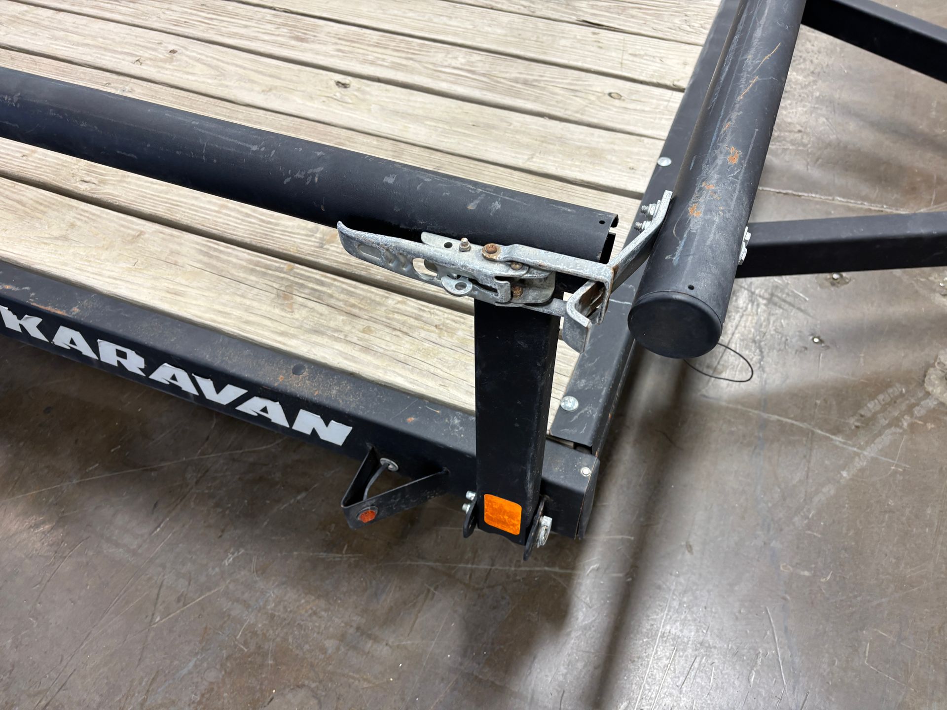 Black boat trailer frame with a lever mechanism and wooden planks. The trailer says 
