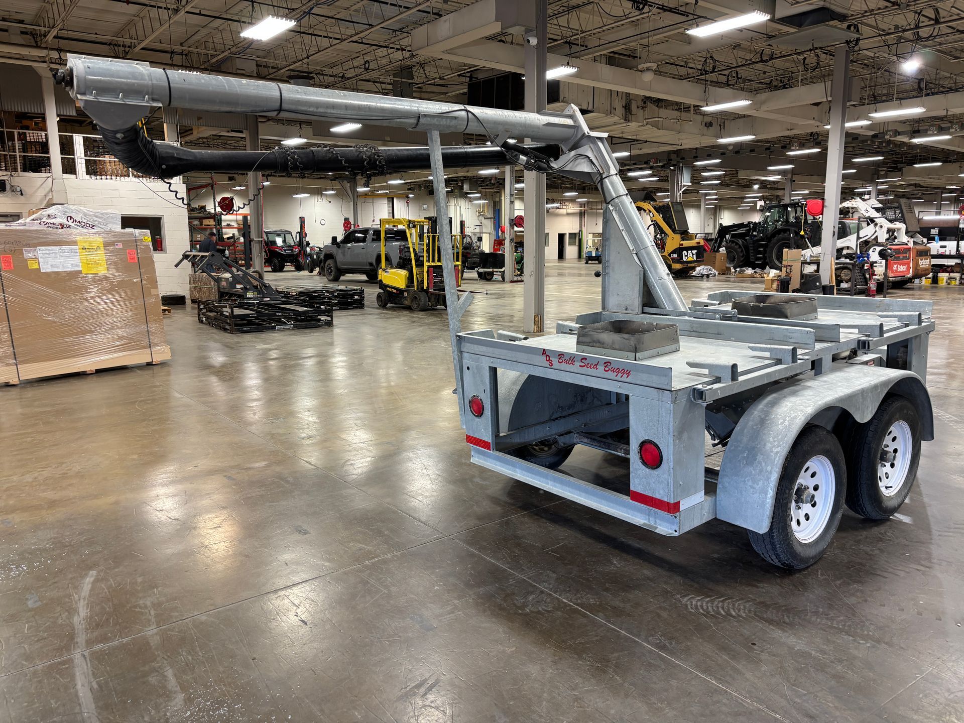 Gray trailer with attached elevated metal arm inside a warehouse.