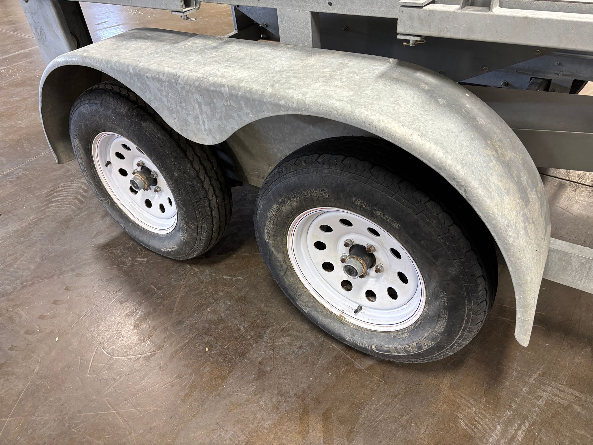 Two trailer wheels with white rims and a silver fender.