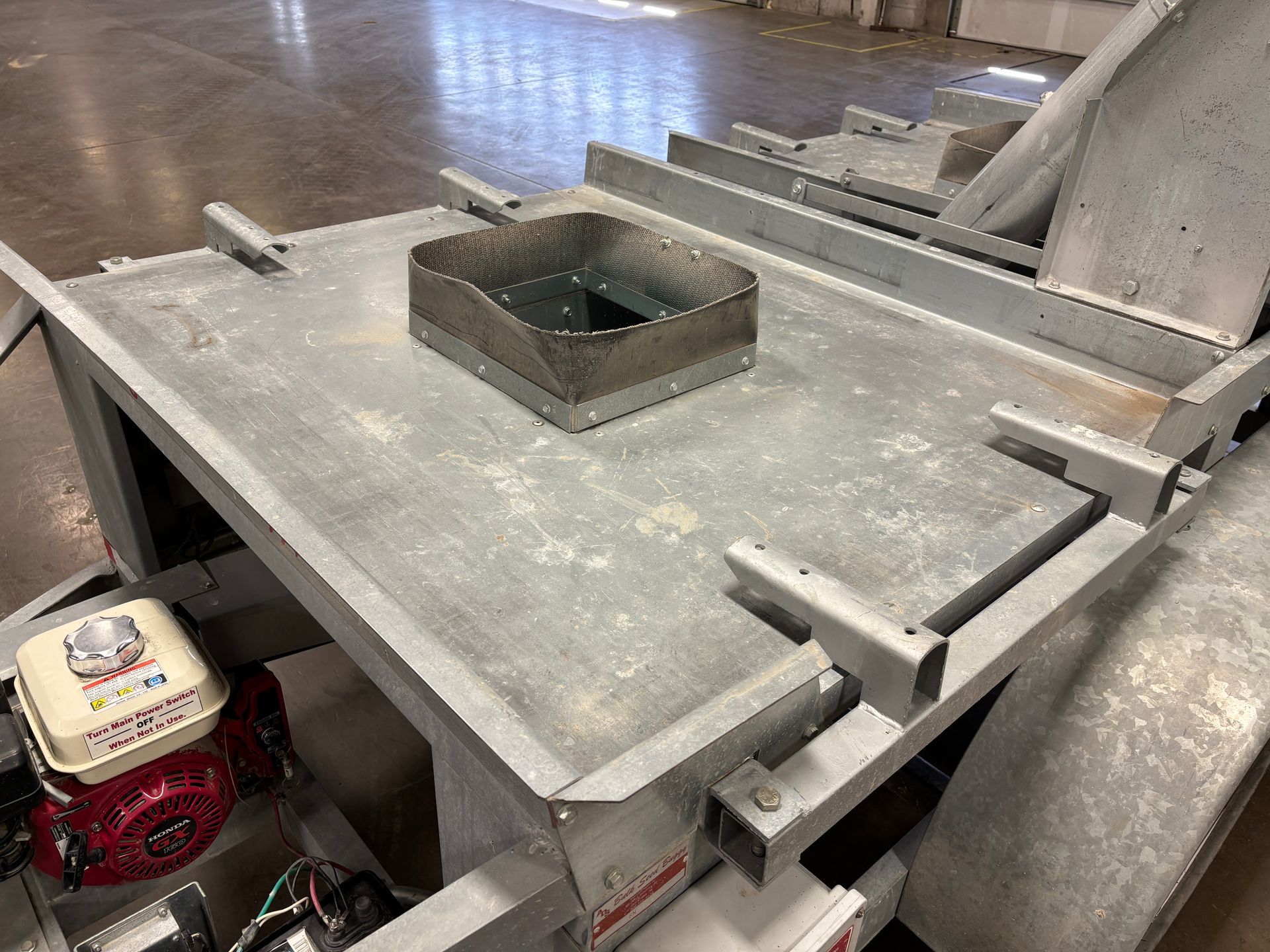 Metal trailer with a square opening, and a small engine on the side.