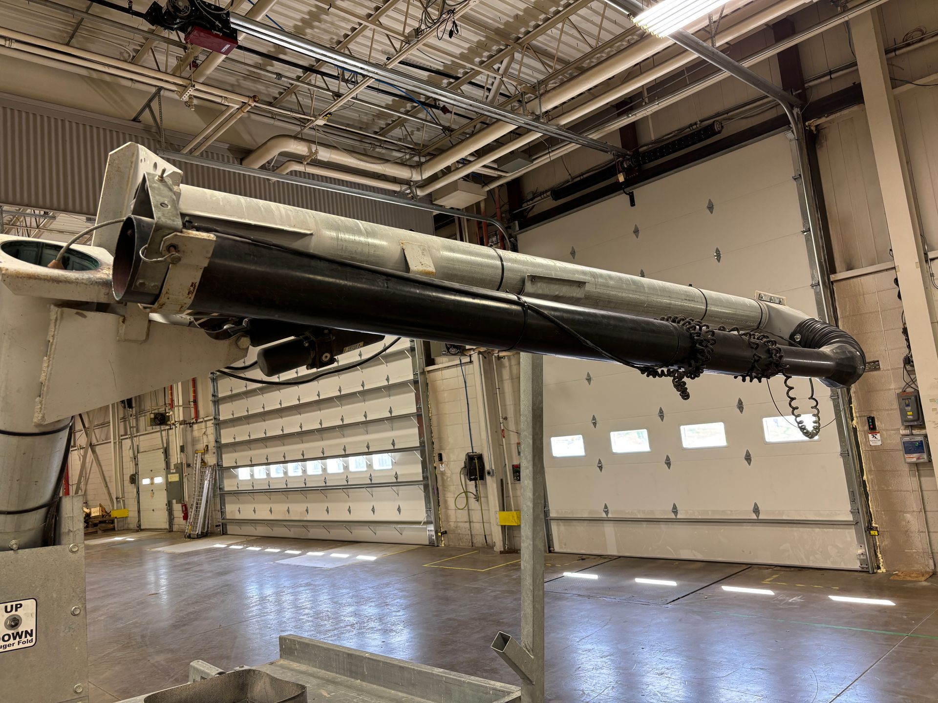 Large industrial arm in a workshop setting with a roll-up door.