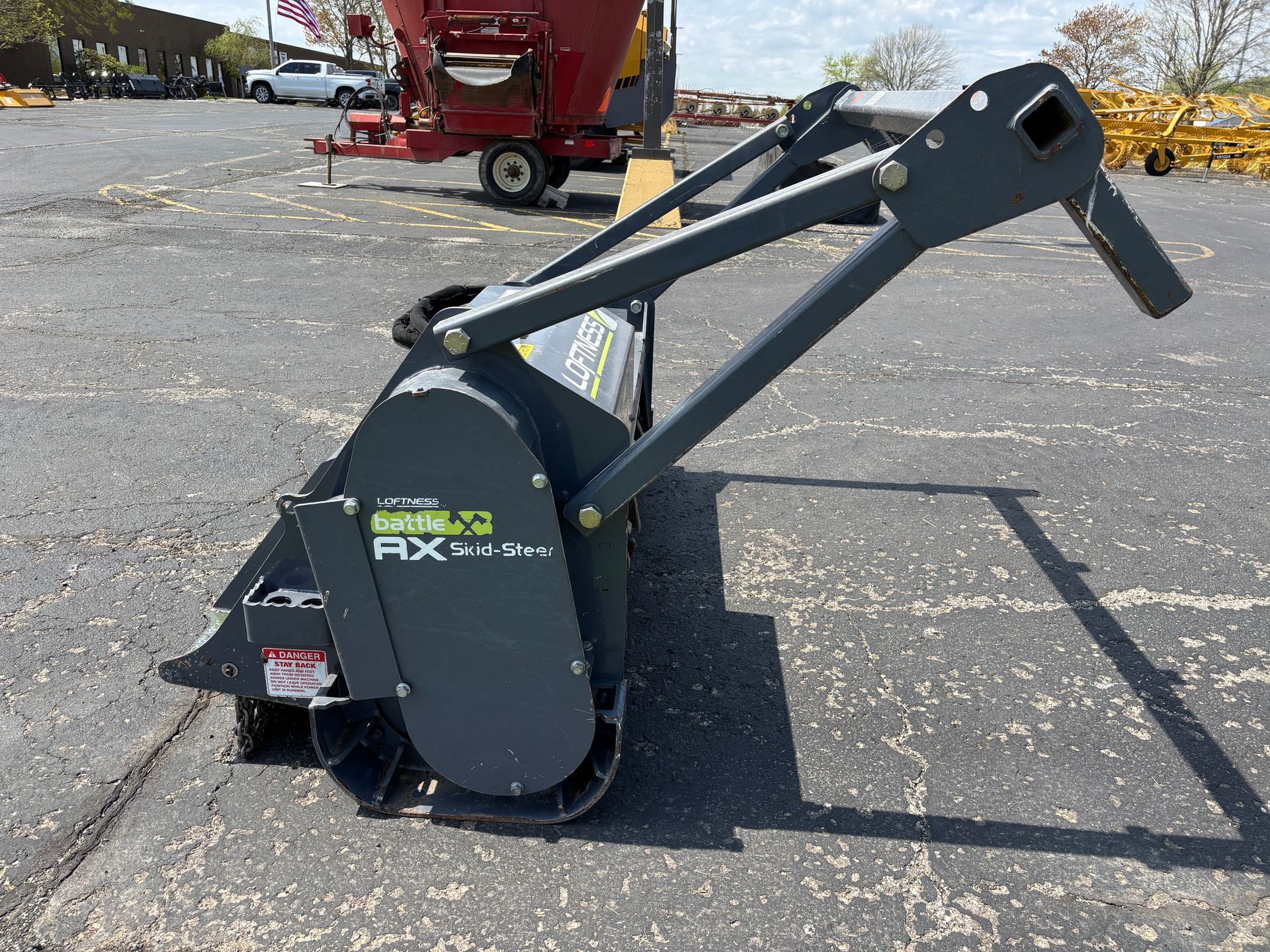 Gray Loftness mulcher on asphalt, with safety bar, on a sunny day, side view.