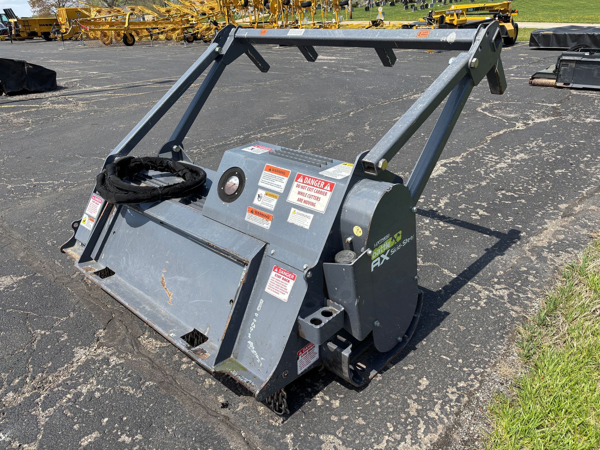 Gray Loftness mulcher on asphalt, with safety bar, on a sunny day, back angle shot.