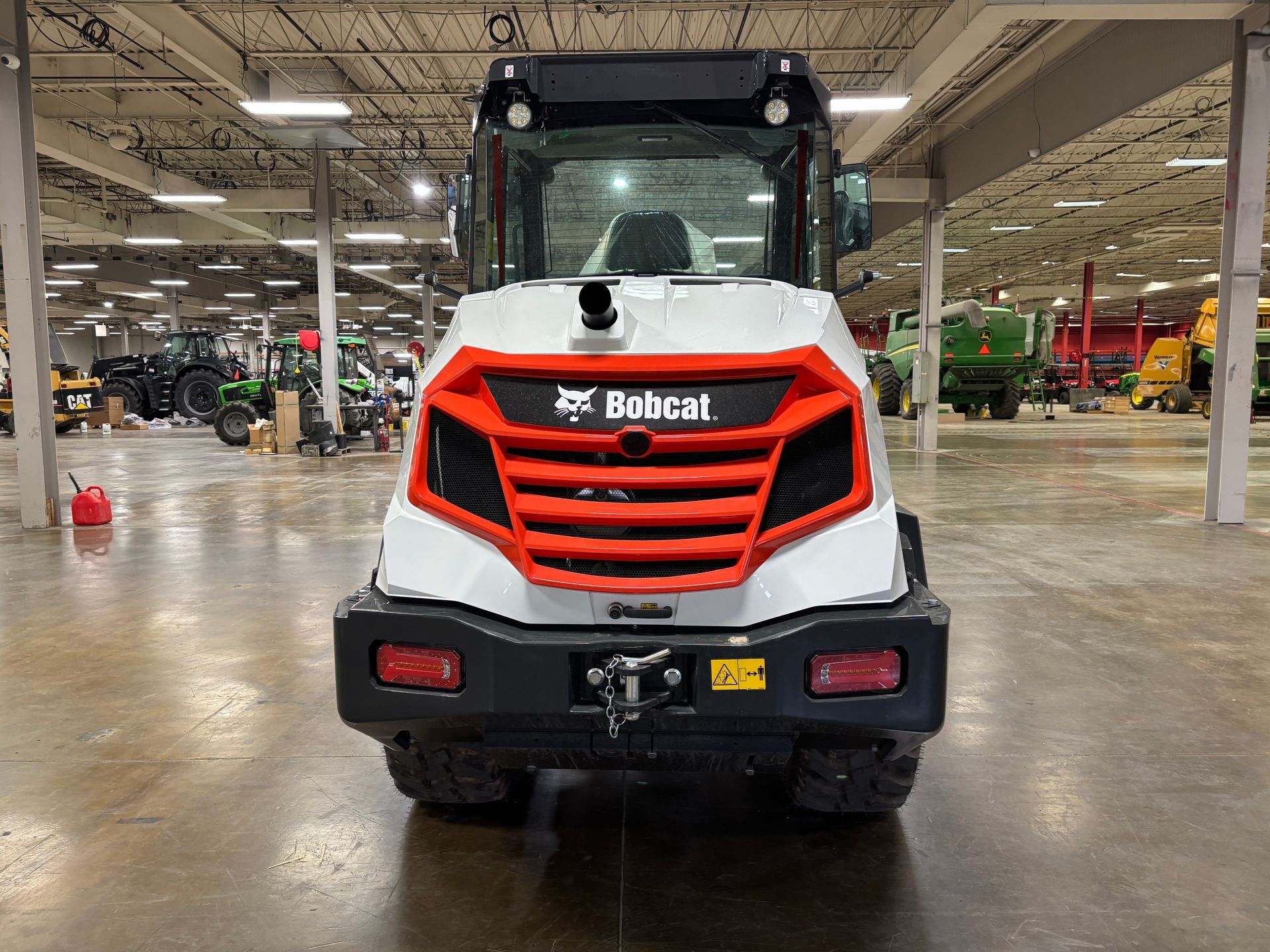 Rear view of a white and orange Bobcat compact loader in a warehouse setting.