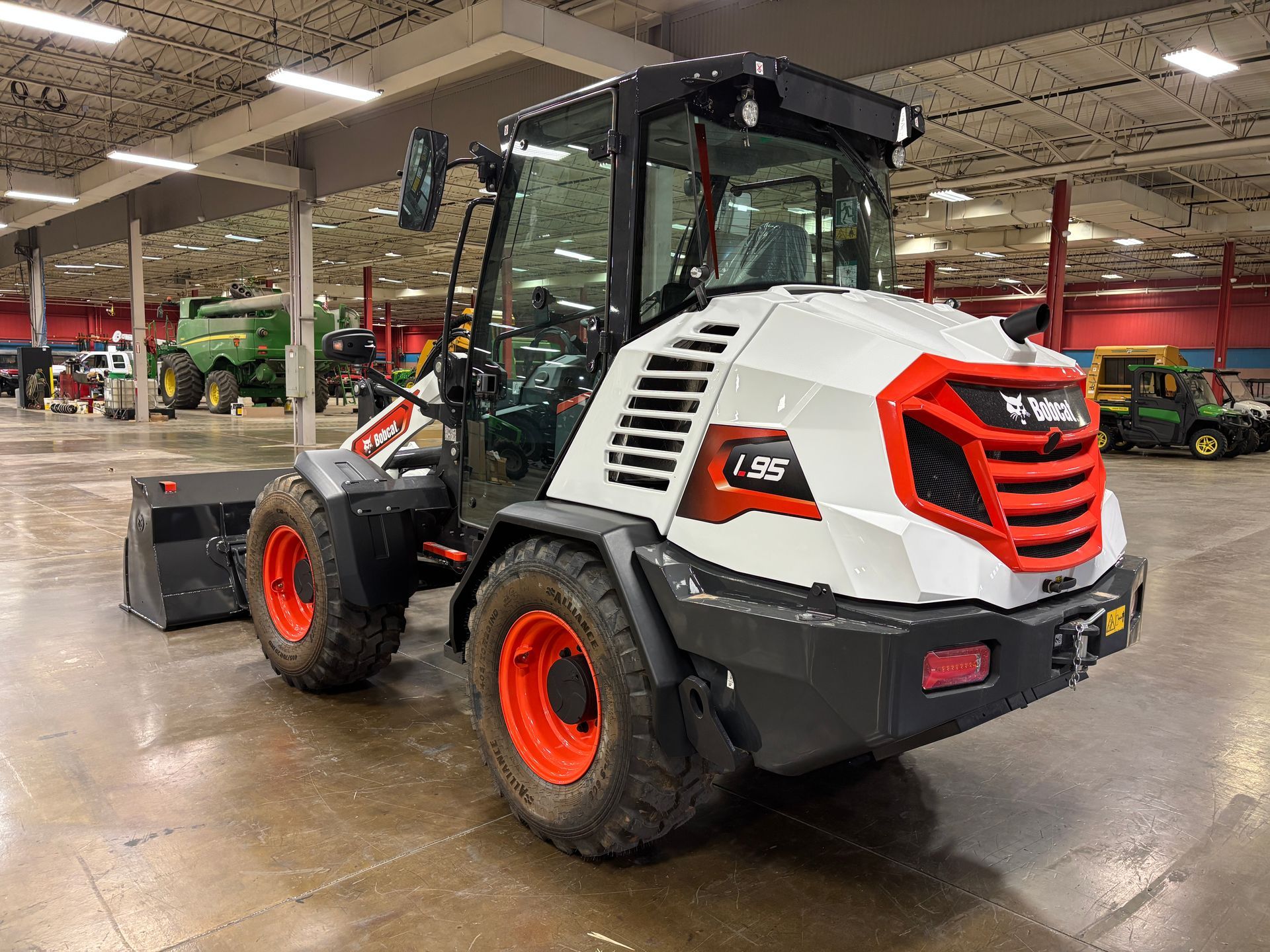White Bobcat L95 wheel loader with orange accents in a warehouse.