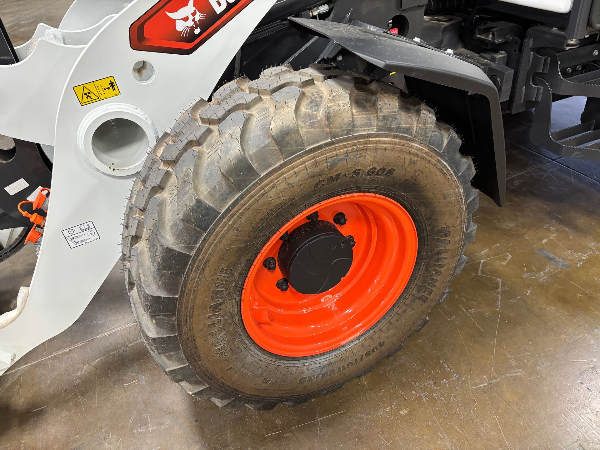Bobcat skid-steer loader wheel with orange rim and black tire.