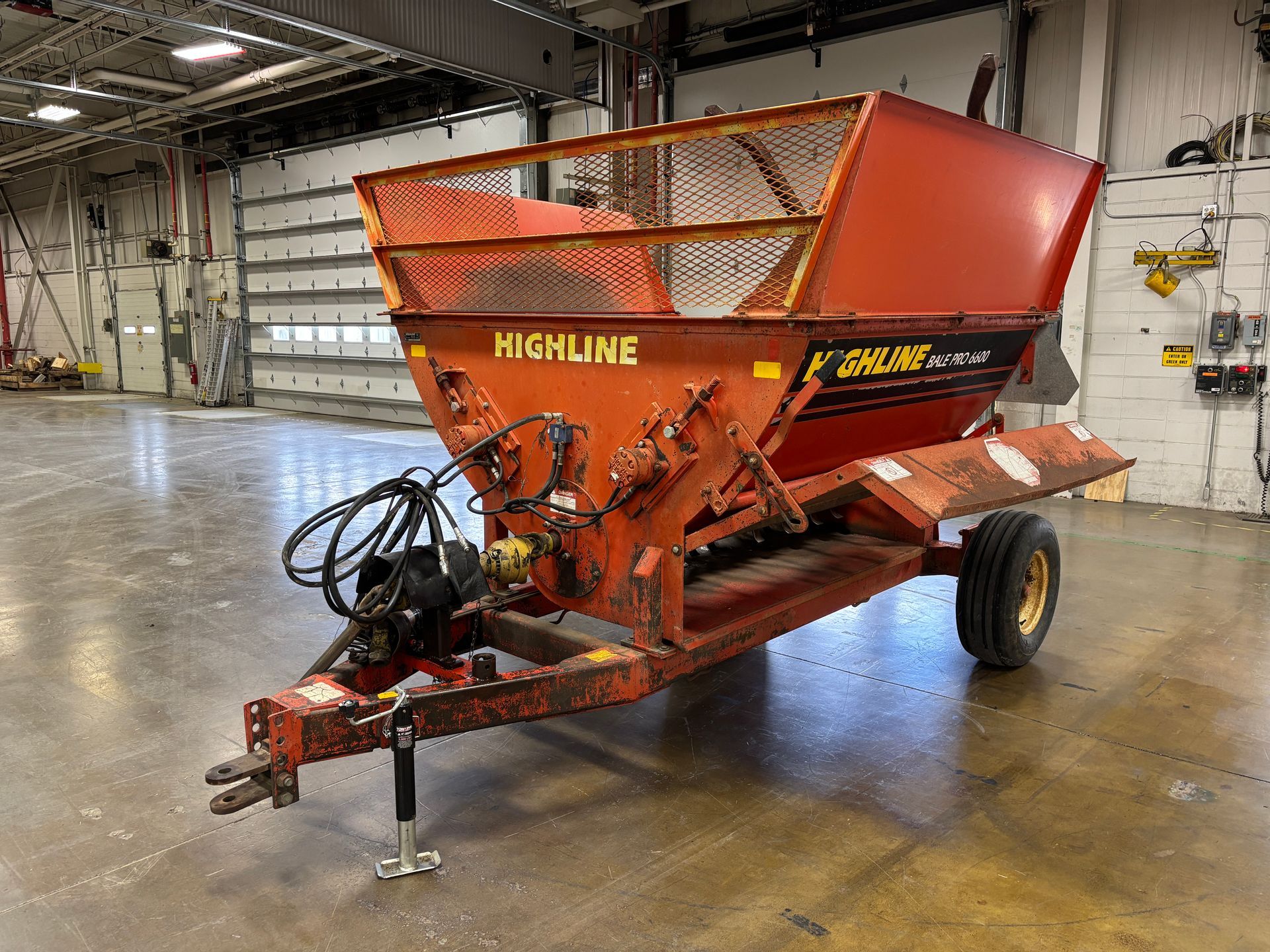 Red Highline bale processor on a trailer, in a warehouse, front angled shot.