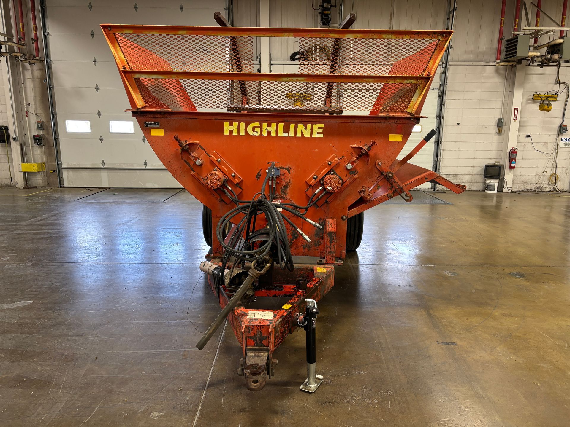 Red Highline bale processor on a trailer, in a warehouse, front shot.