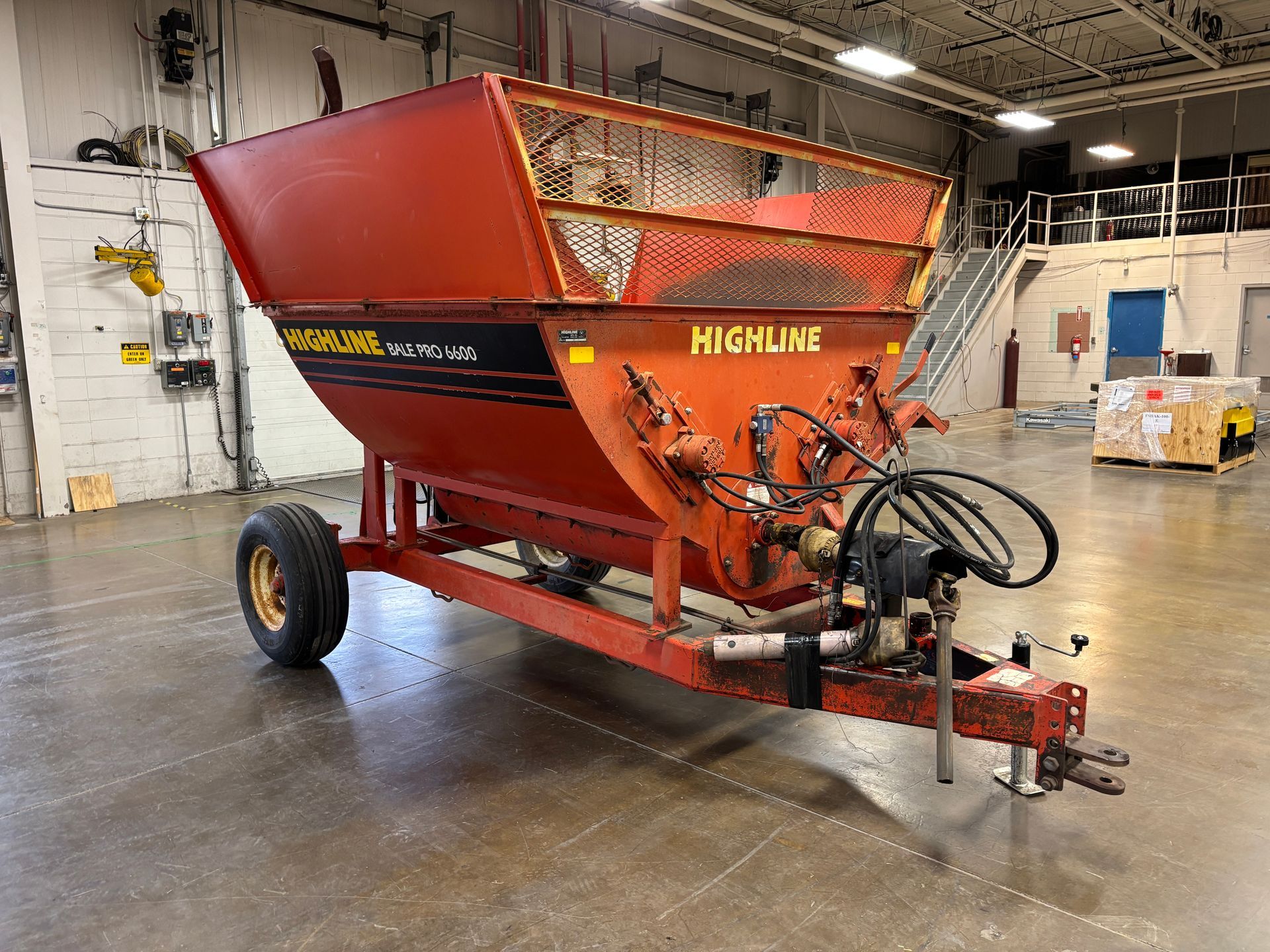 Red Highline bale processor on a trailer, in a warehouse, front angled shot.