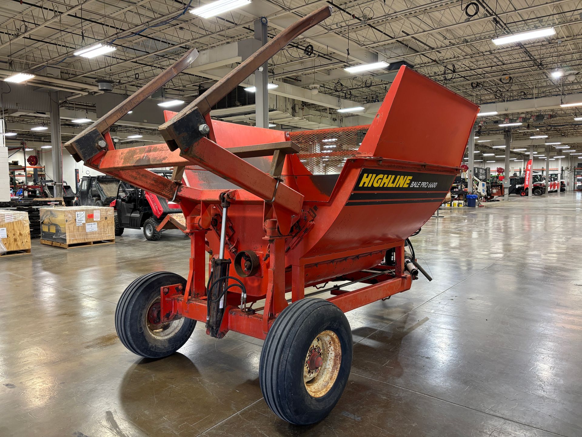 Red Highline bale processor on a trailer, in a warehouse, back angled shot.