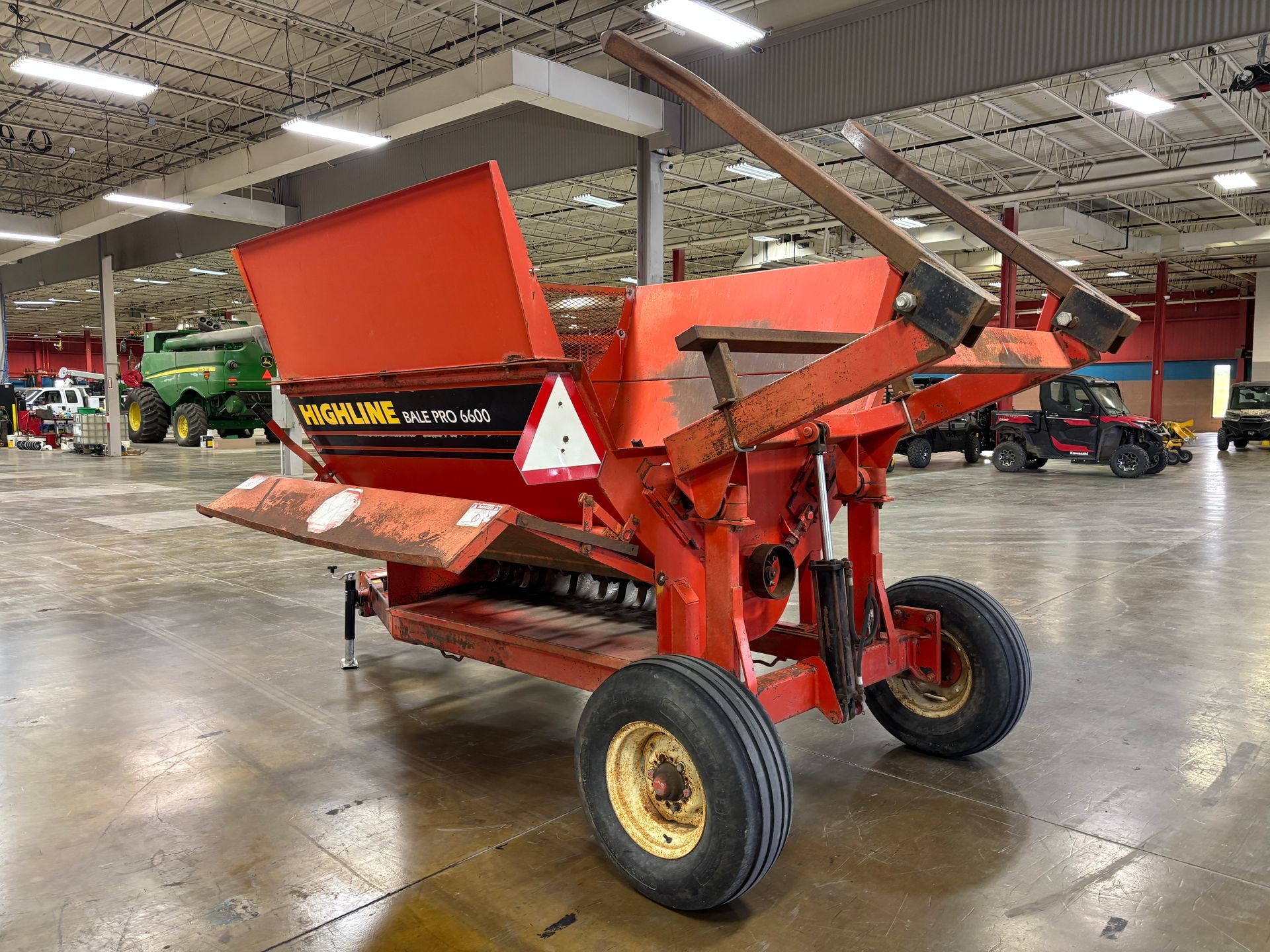 Red Highline bale processor on a trailer, in a warehouse, back angled shot.