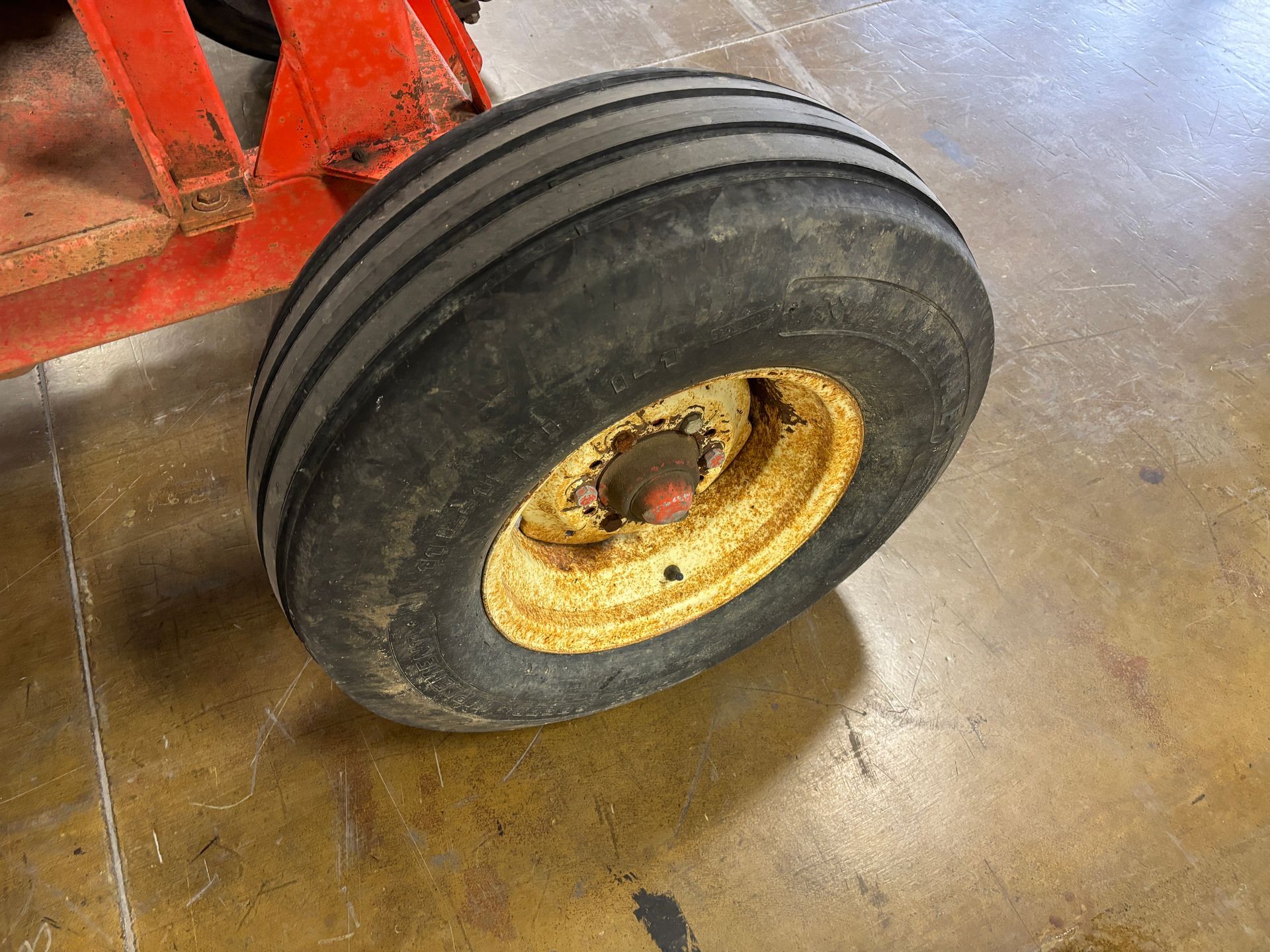 Red Highline bale processor on a trailer, in a warehouse, tire shot.