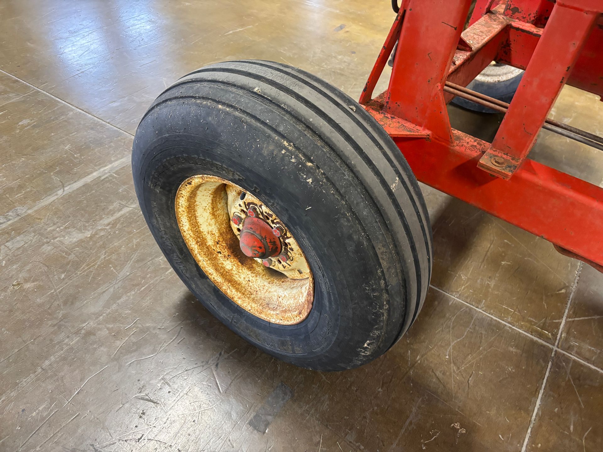 Red Highline bale processor on a trailer, in a warehouse, tire shot.