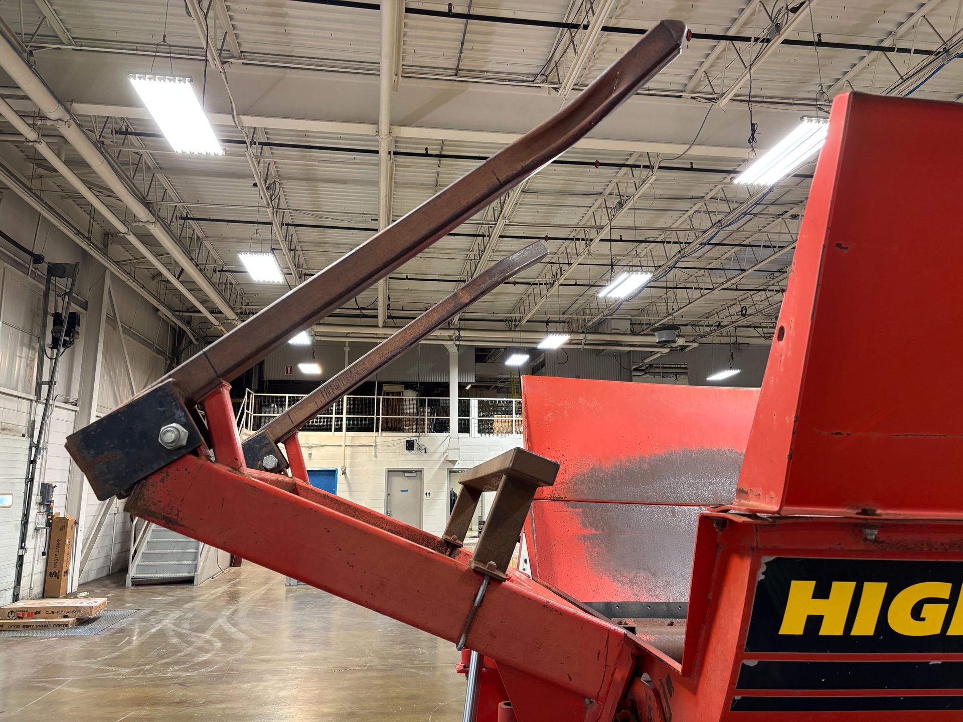 Red bale processor with raised arms indoors.