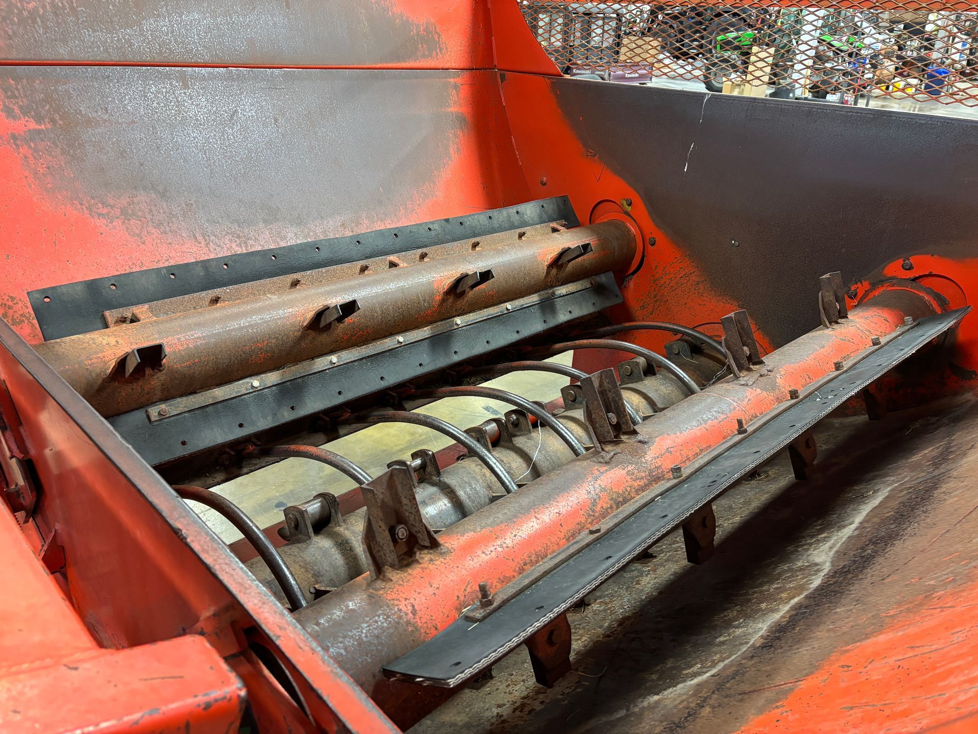 Interior view of a red bale processor machine with rusty rotating auger and blades, used for composting.