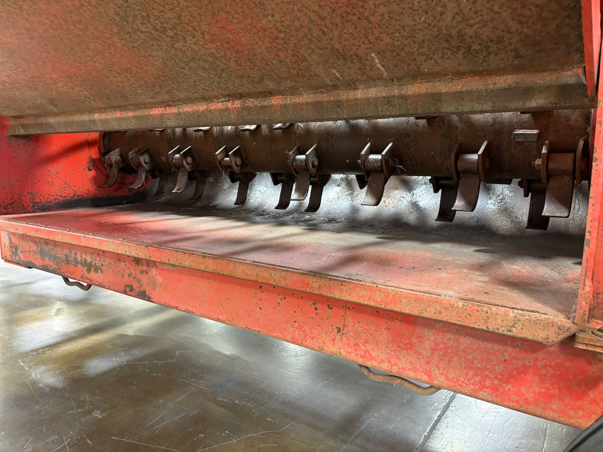 Close-up view of a red bale processor  with a row of metal blades.