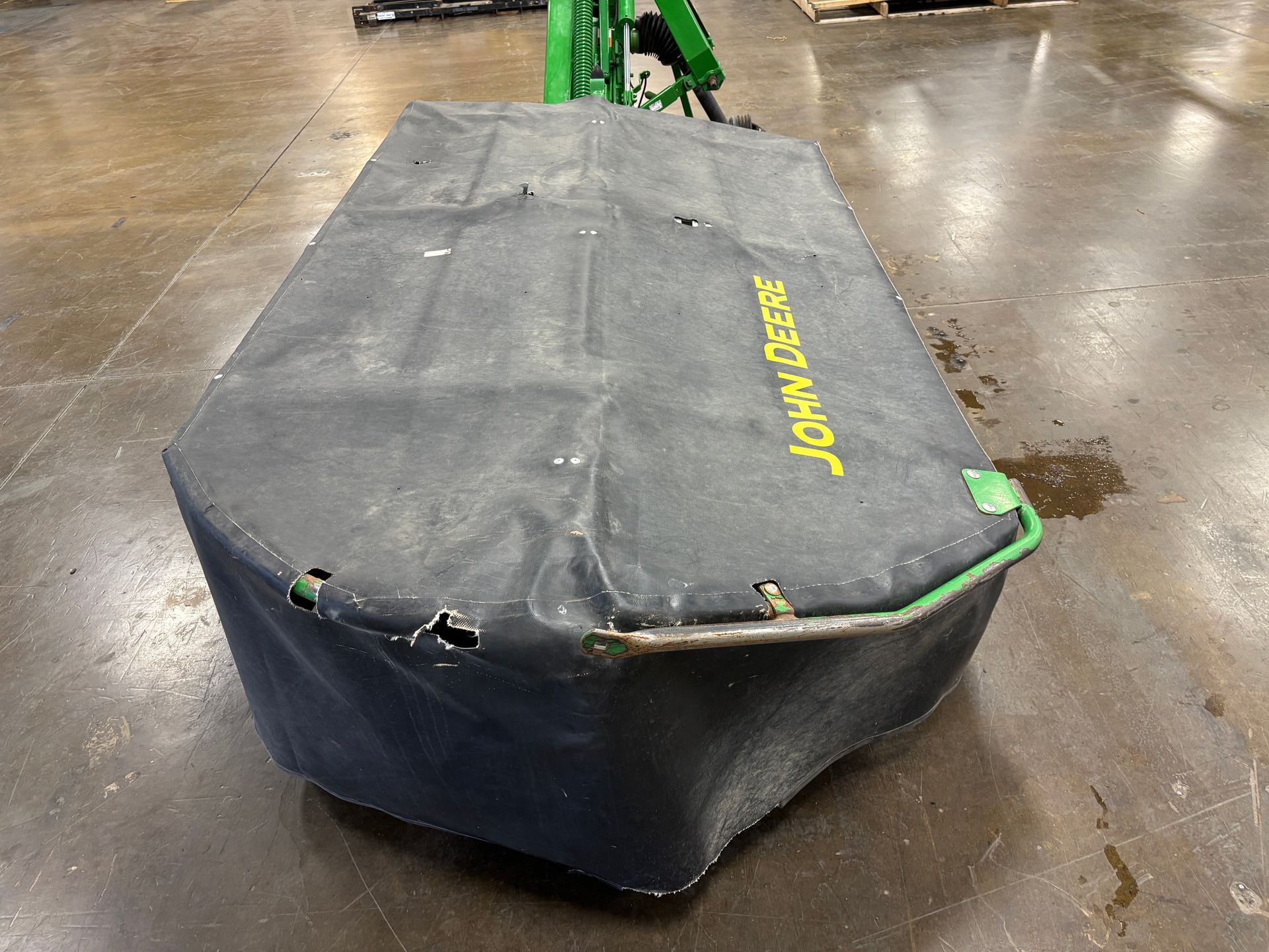 Black John Deere mower cover on a concrete floor.