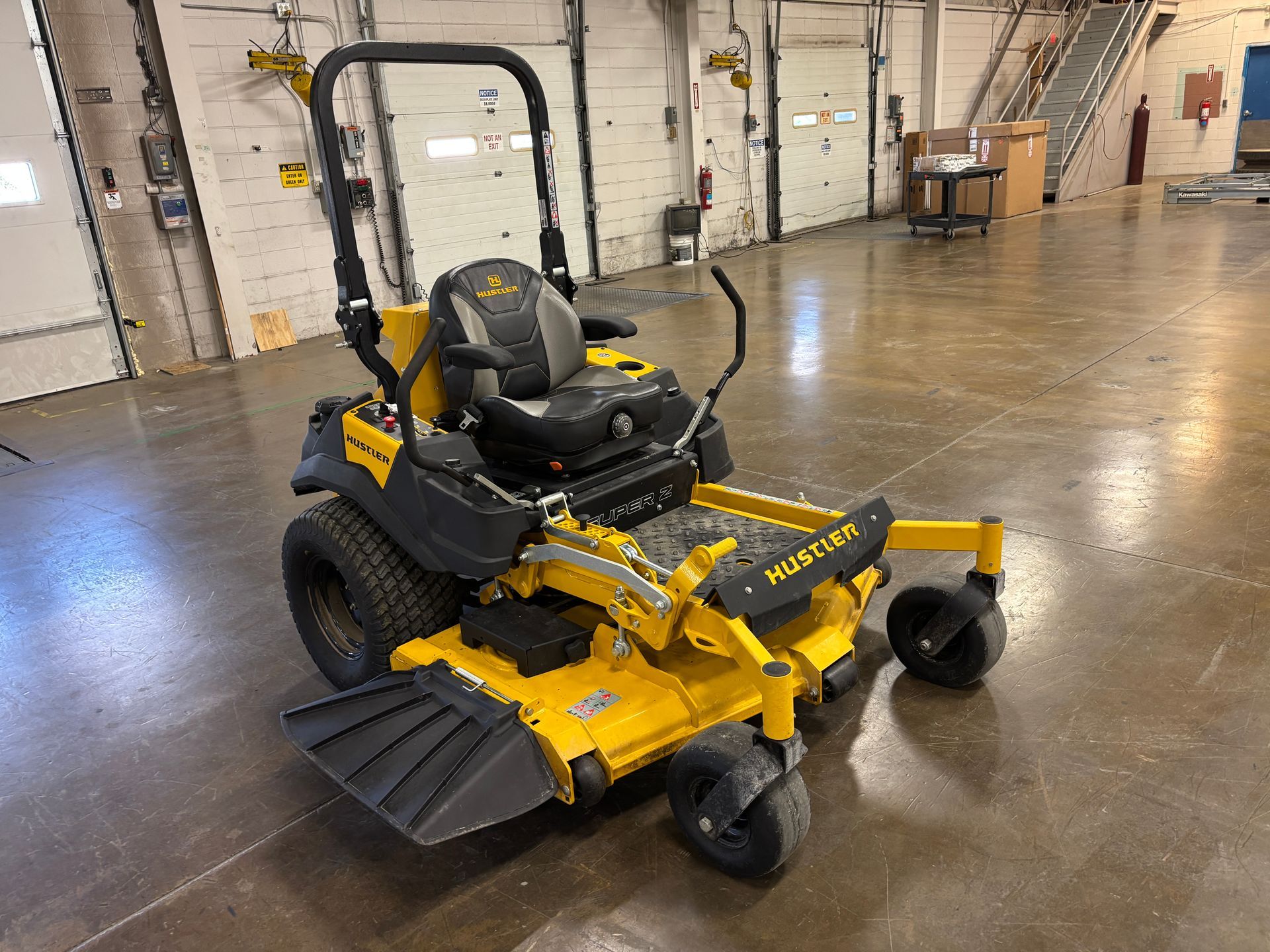 Yellow and black Hustler zero-turn mower in an industrial setting.