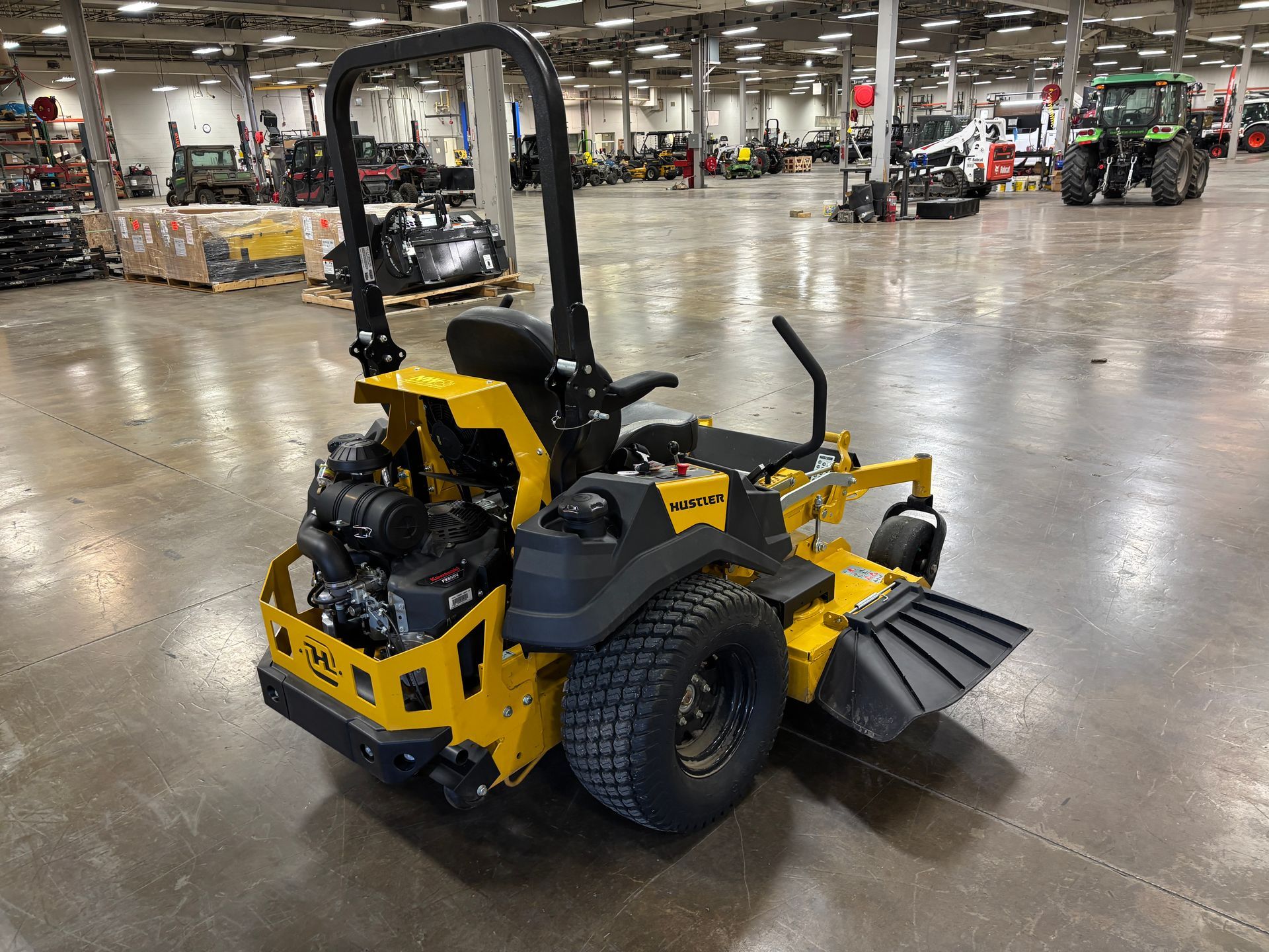 Yellow zero-turn lawn mower on a concrete floor in a warehouse.