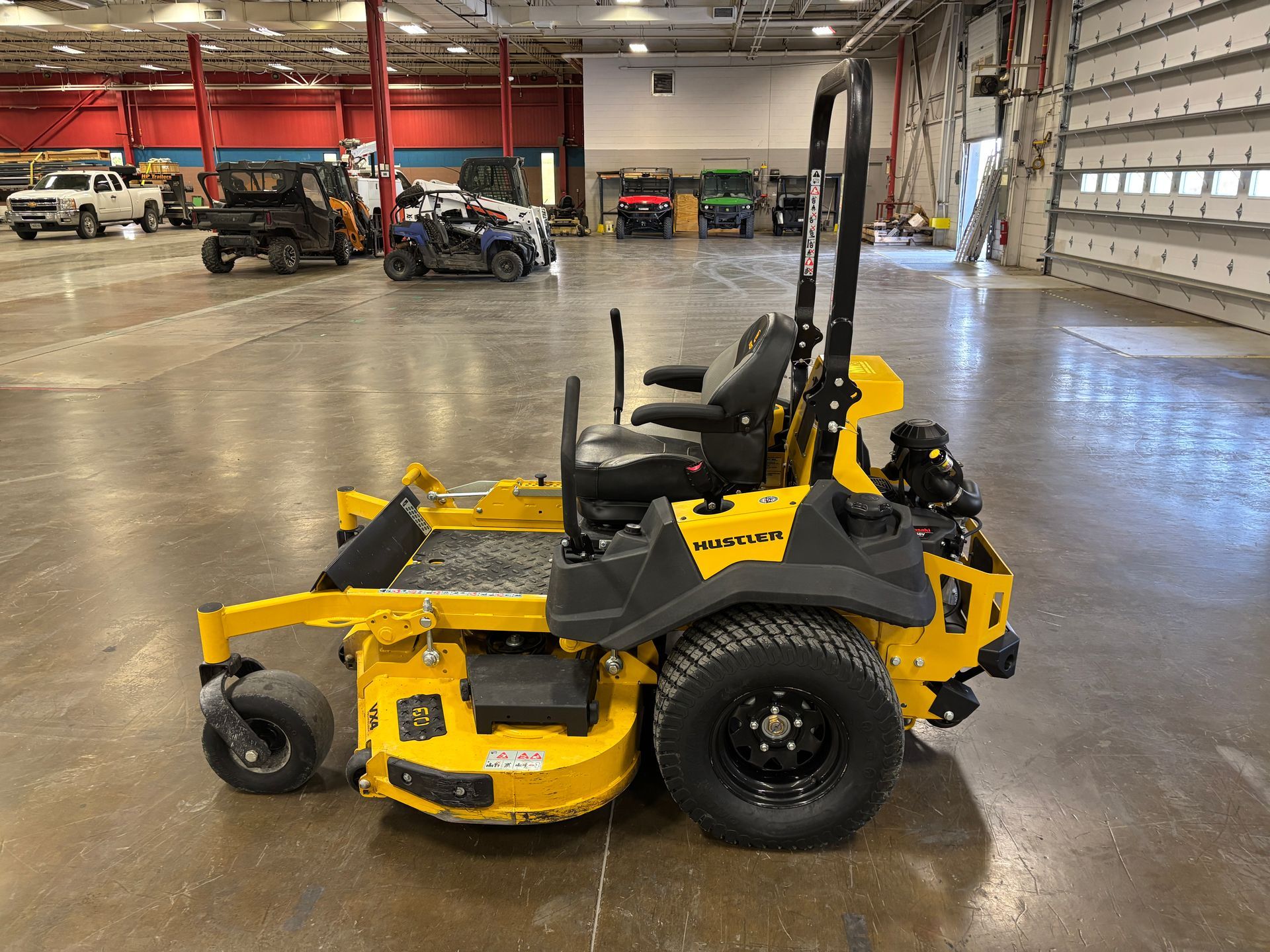 Yellow and black commercial zero-turn lawnmower in a large indoor space.