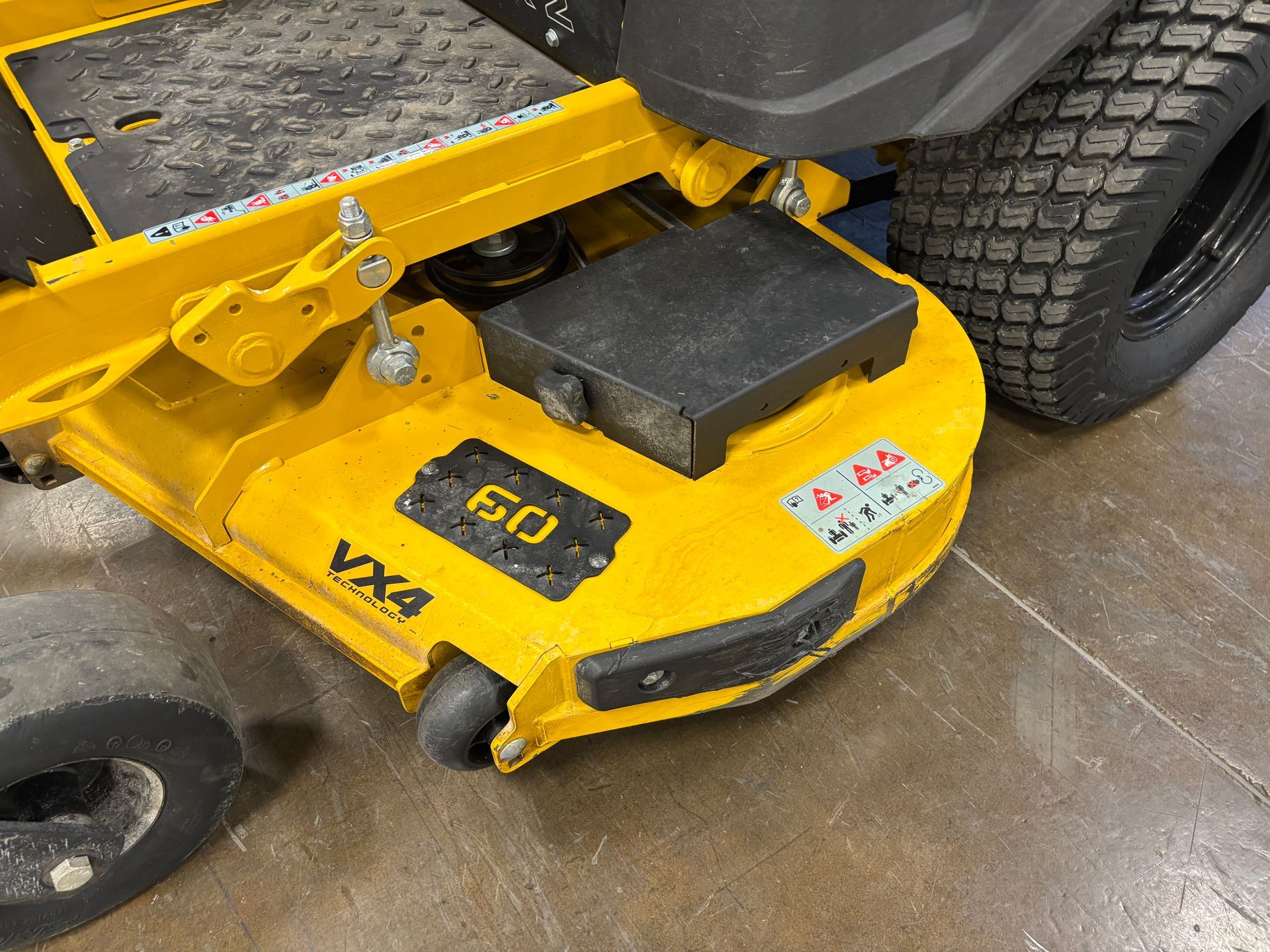 Yellow zero-turn mower with a 60-inch deck, positioned indoors on a concrete floor.