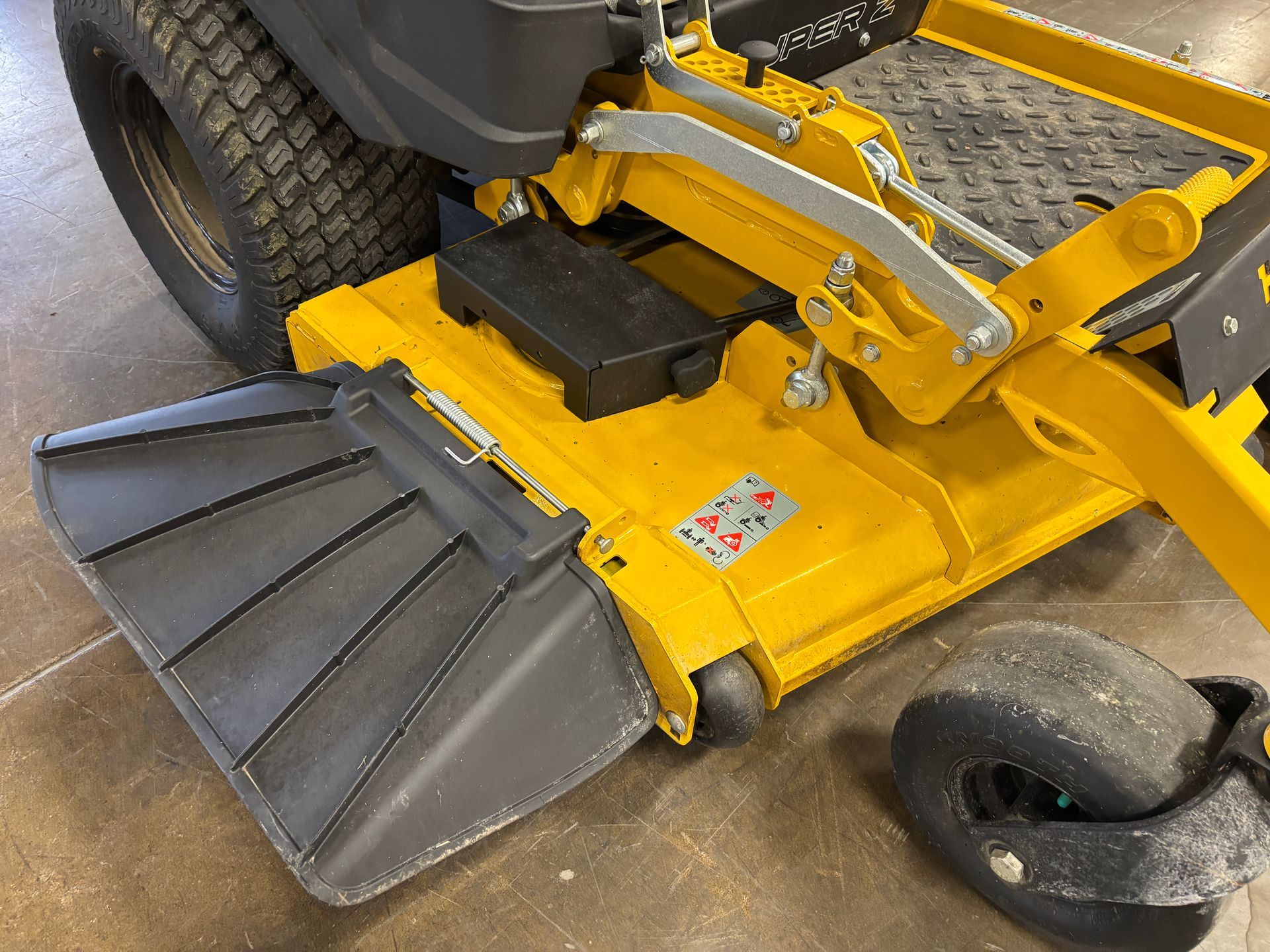 Yellow commercial lawn mower with black deflector, and right wheel.