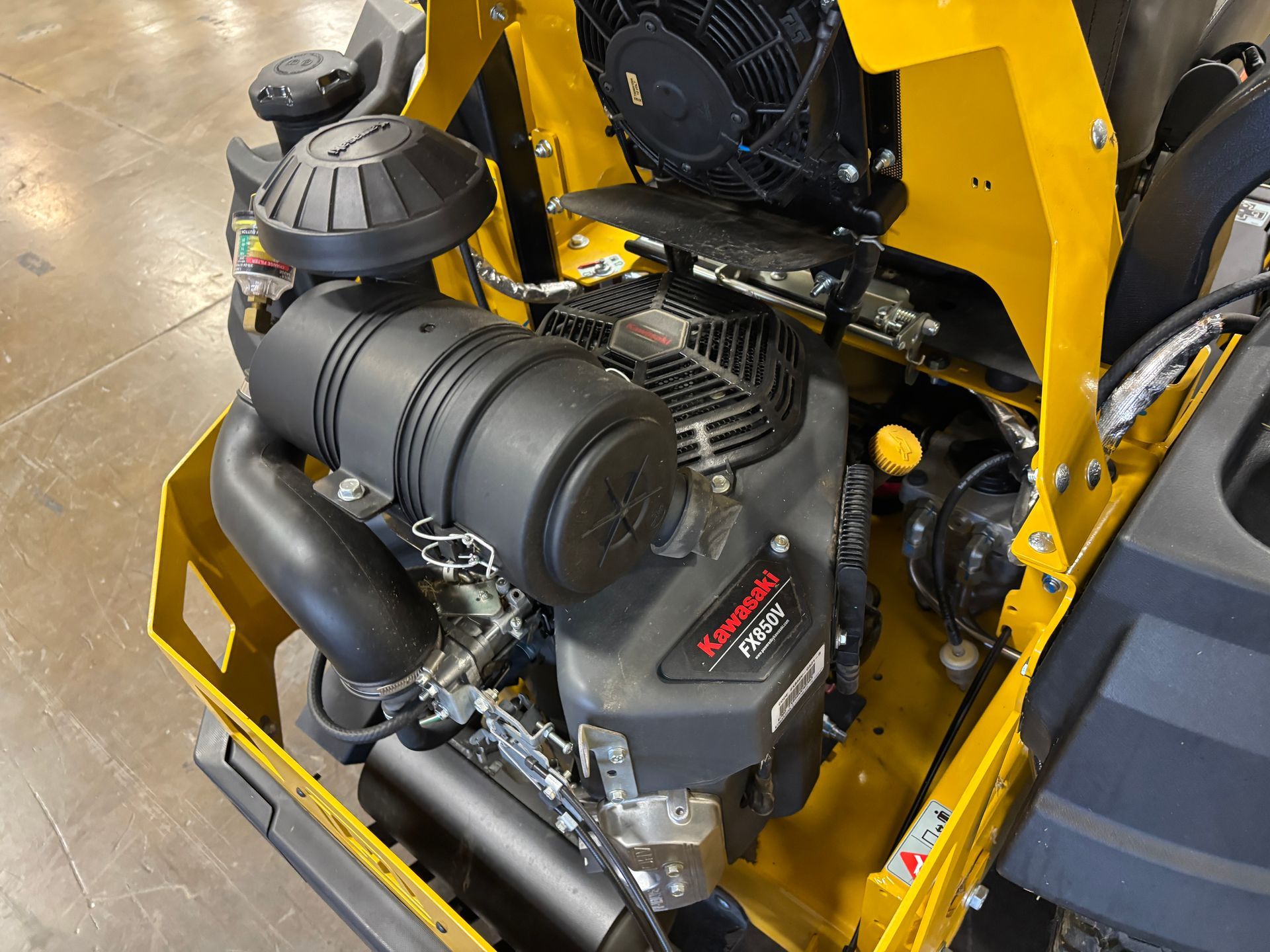 Yellow and black engine in a piece of machinery. Kawasaki engine label visible.