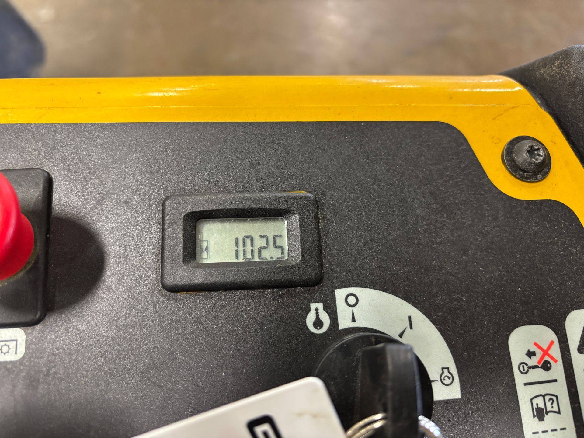 Close-up of a machine control panel. A digital display shows 102.5. Yellow and black exterior, with a key and button visible.