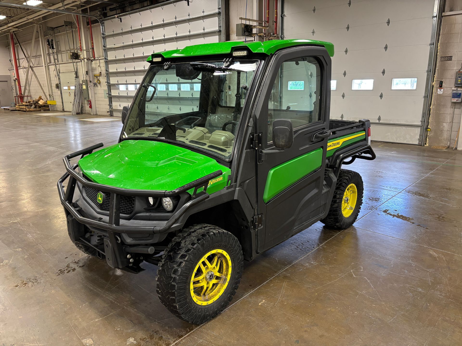 Green and black John Deere Gator utility vehicle with yellow wheels.