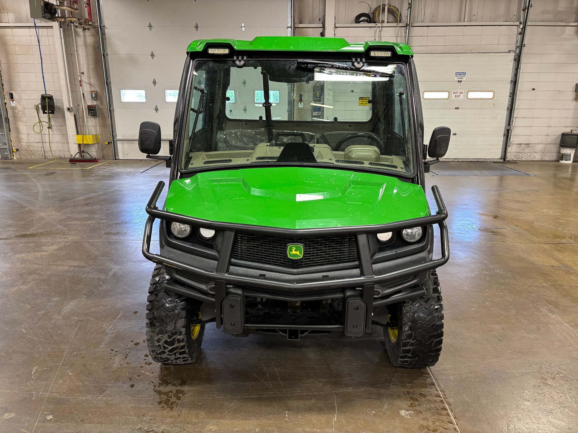 Green John Deere Gator utility vehicle with a front bumper, in a garage.