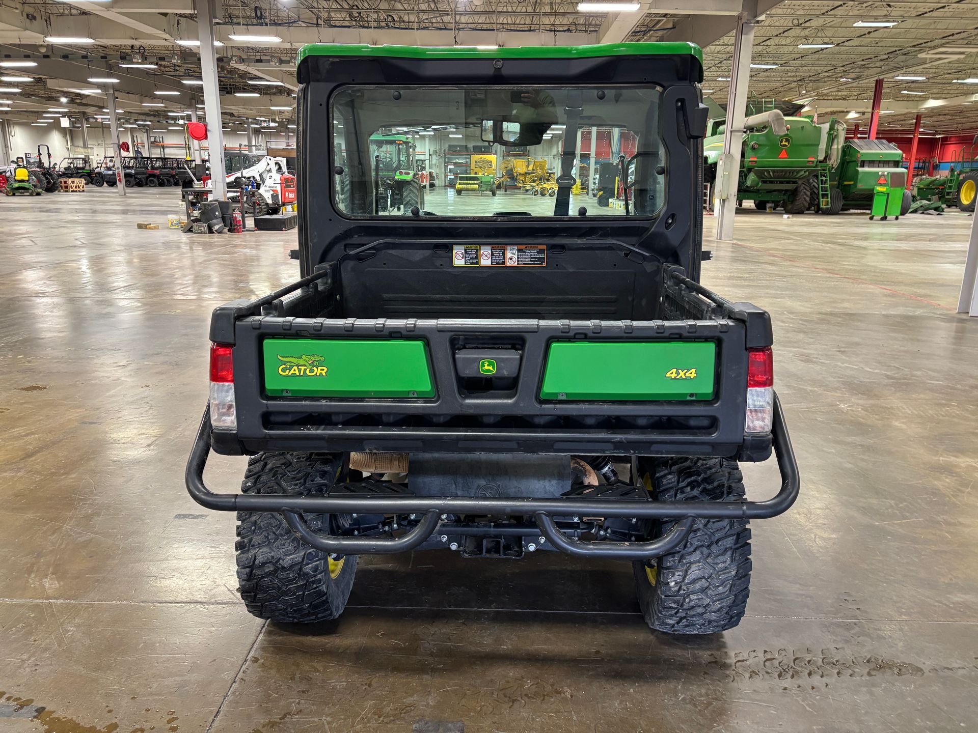 Rear view of a green and black John Deere Gator utility vehicle in a warehouse.